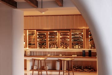 a bar with shelves of wine and stools