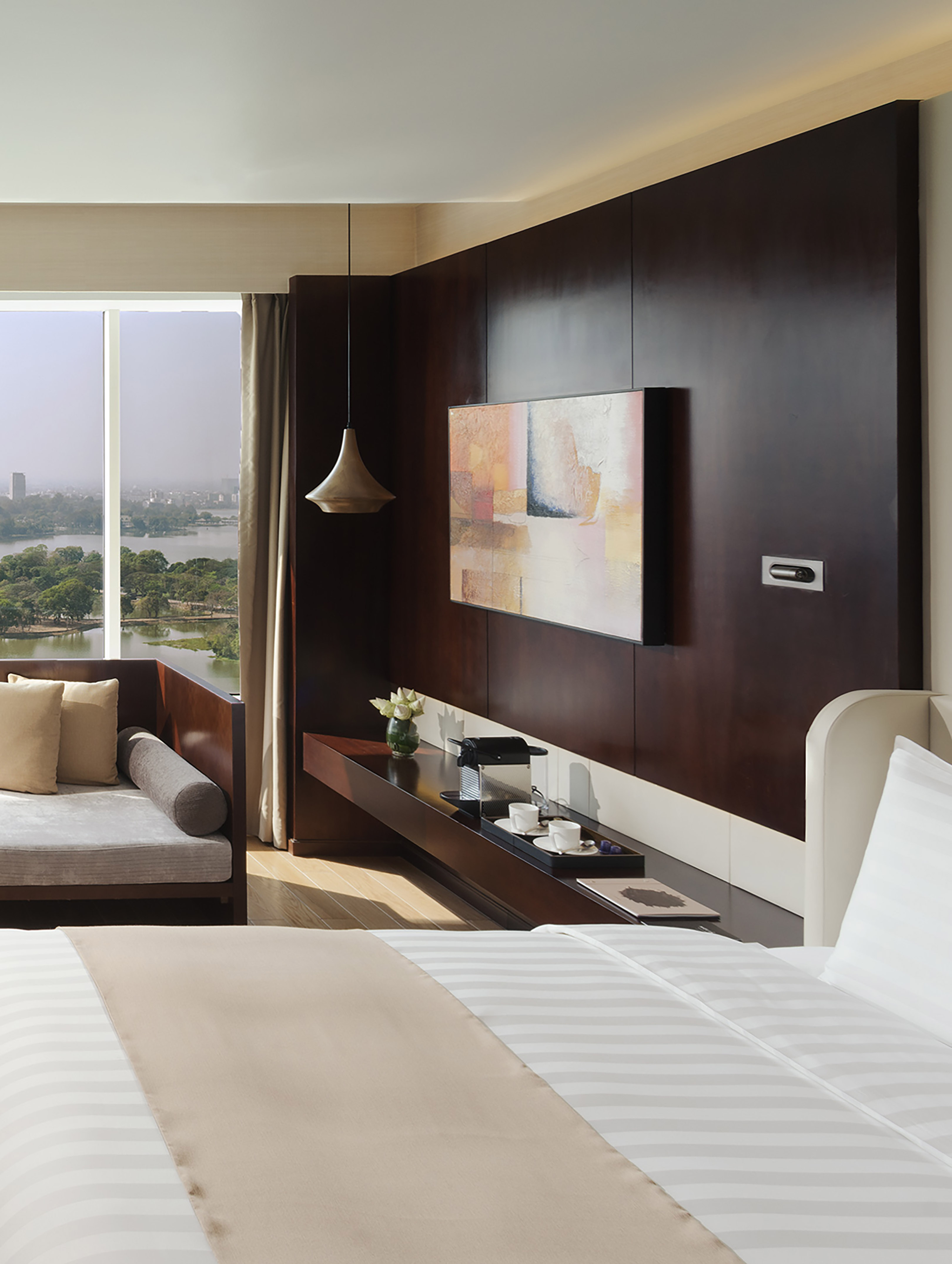 Modern hotel room with lake view, dark wood wall, and contemporary artwork.