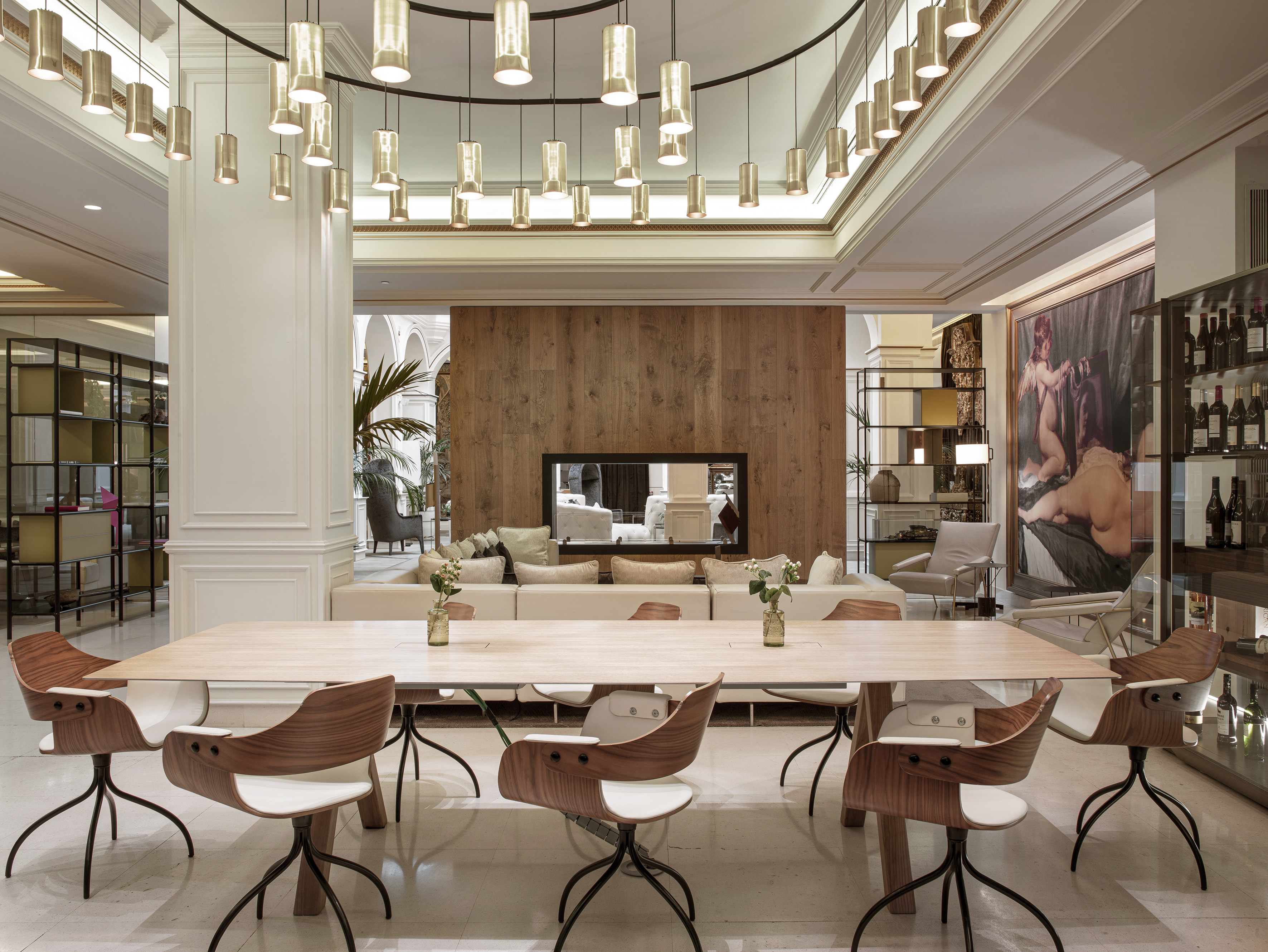 Modern hotel lounge with long table, stylish chairs, and elegant pendant lighting.