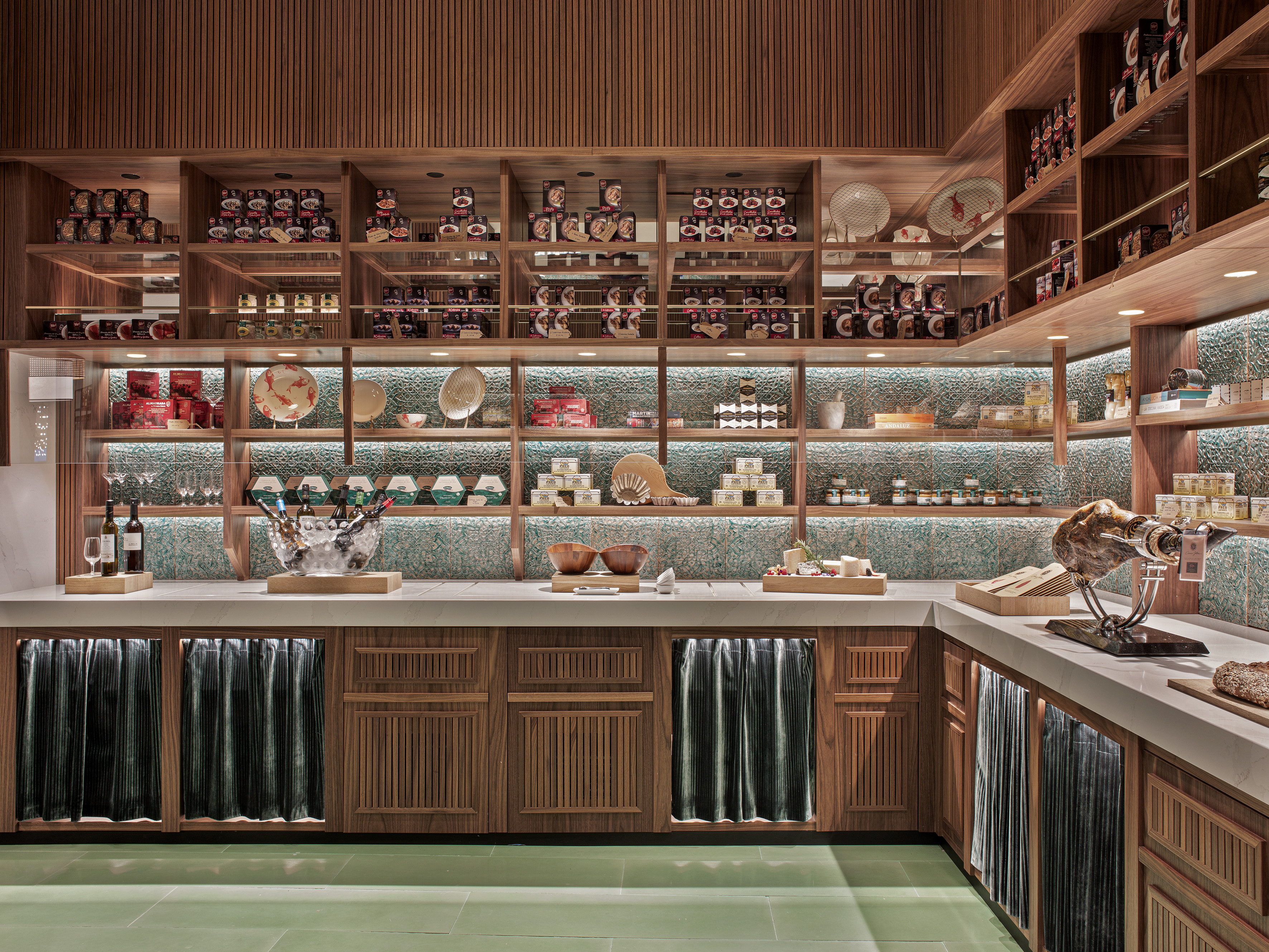 Gourmet deli: wooden shelves displaying food, jamón, wine, and cheese.