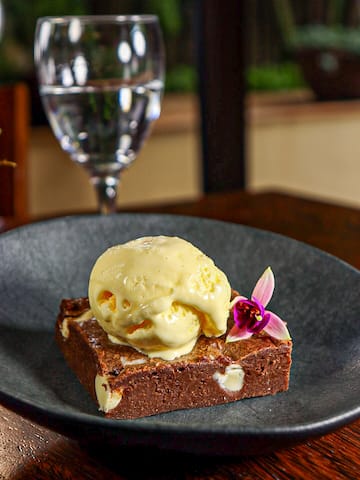 a brownie with ice cream on top and a glass of water