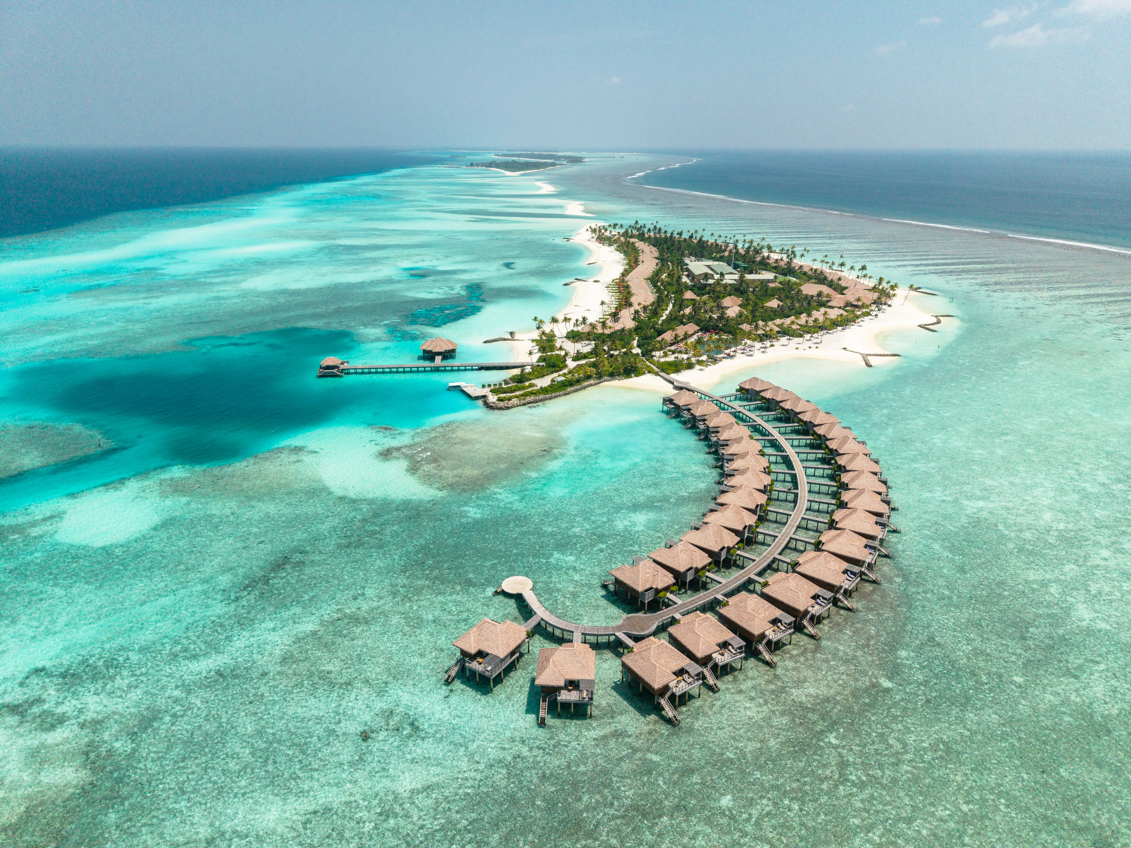 Maldives resort: overwater villas, tropical island, and turquoise ocean reef.