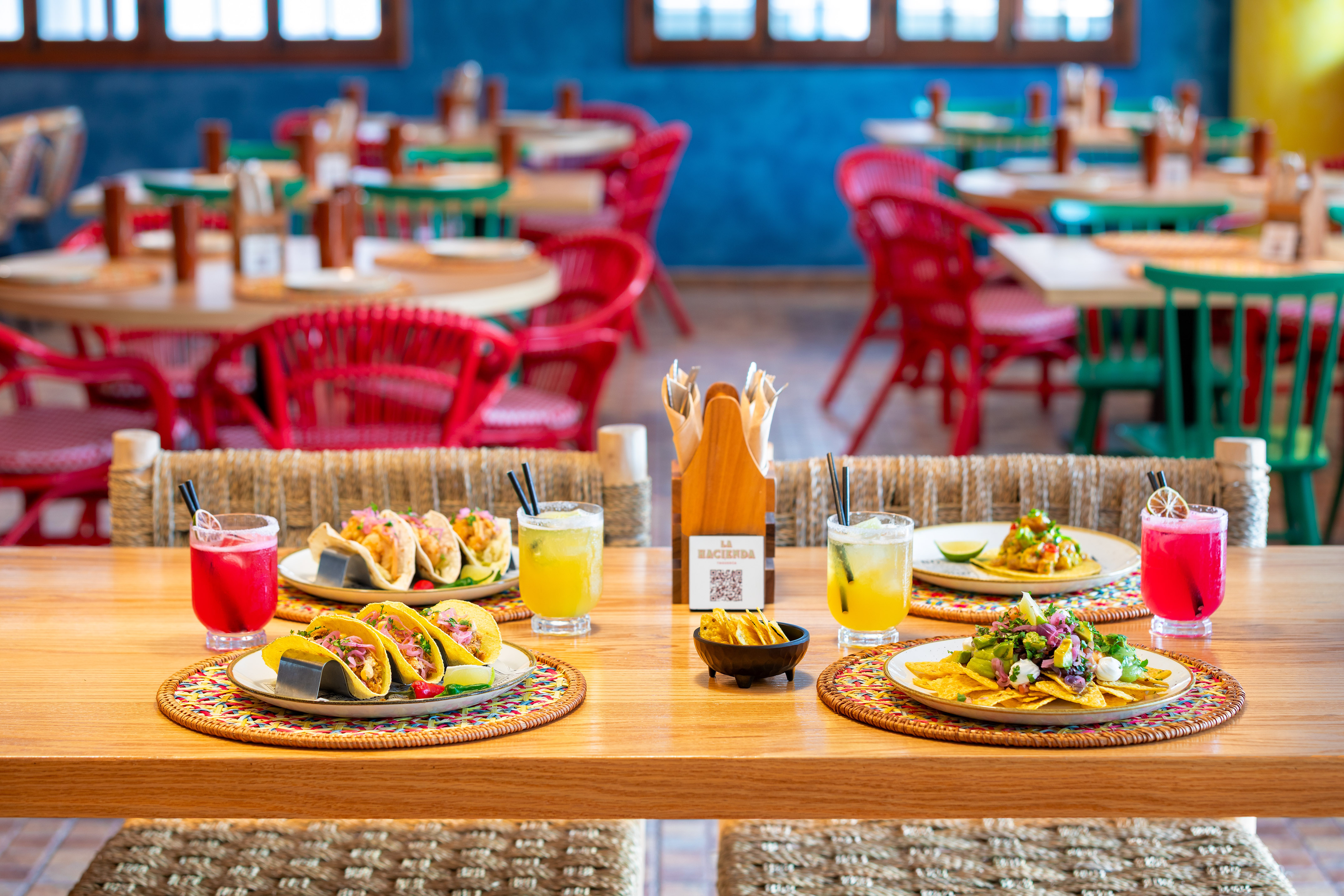 Vibrant Mexican restaurant table with tacos, nachos, and colorful cocktails.