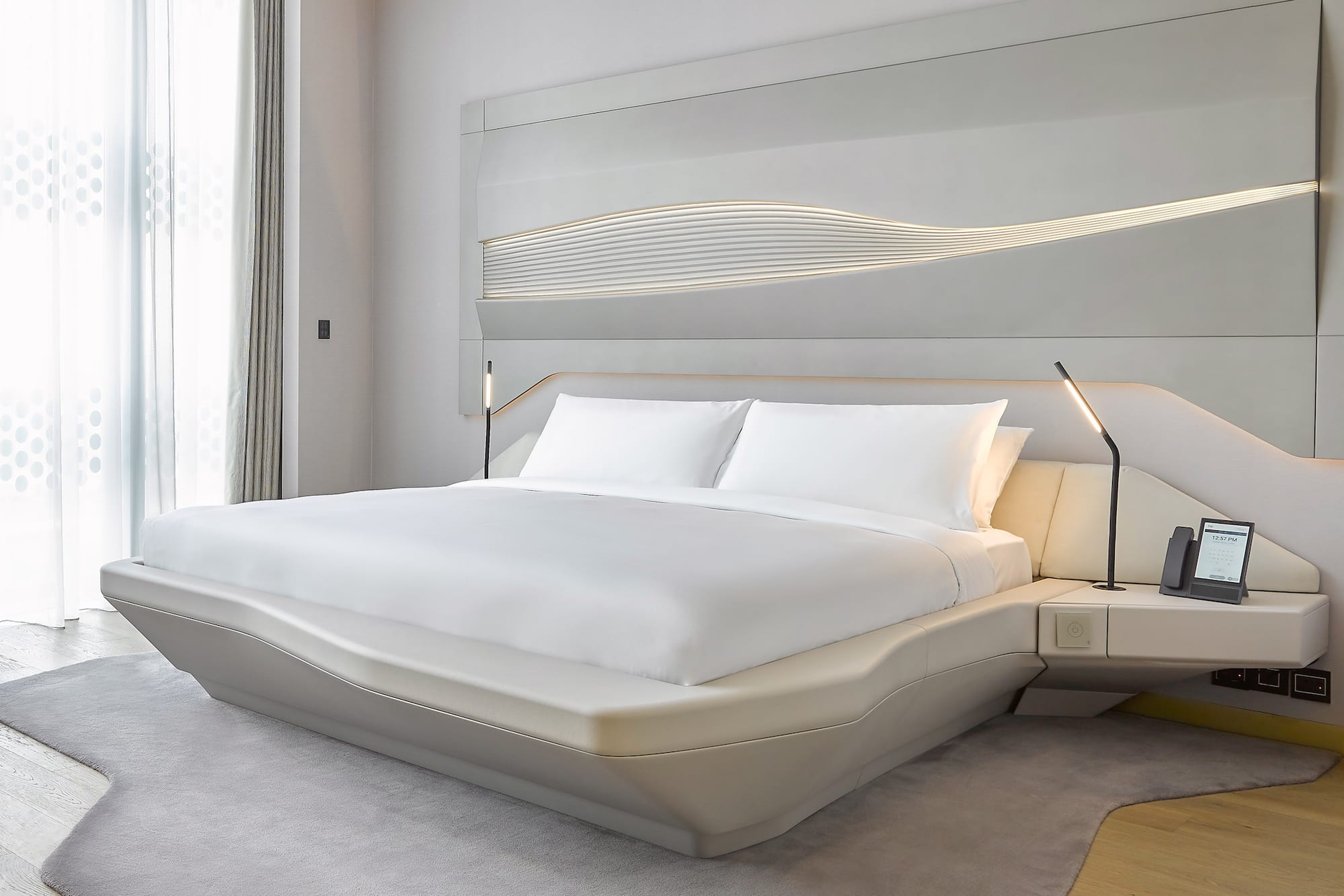 a bed with white sheets and a lamp on the side