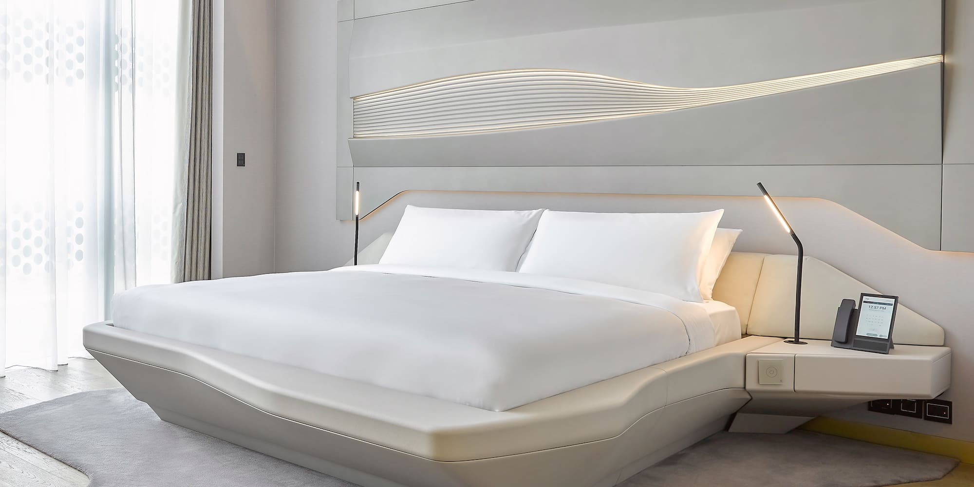 a bed with white sheets and a lamp on the side