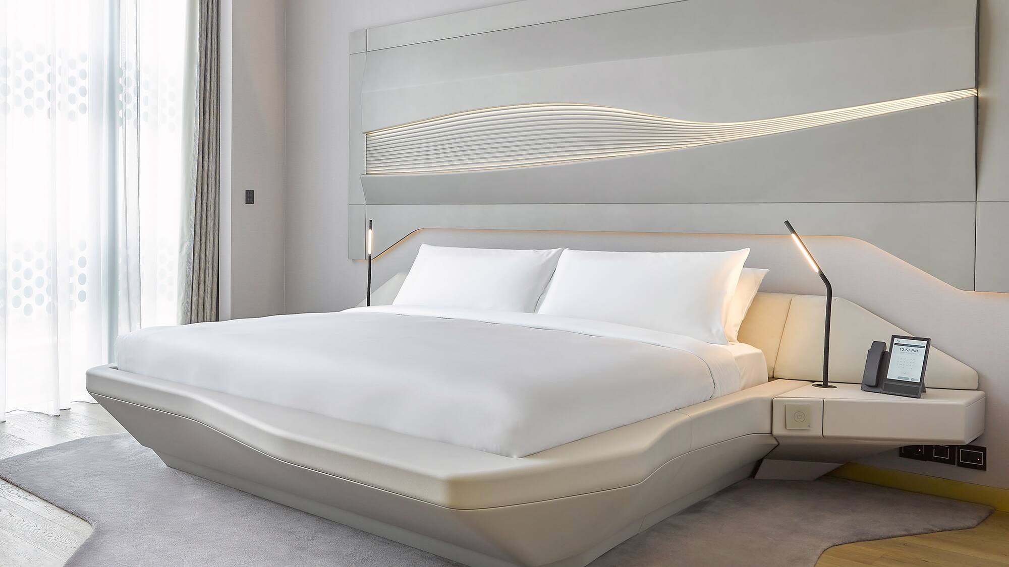 a bed with white sheets and a lamp on the side