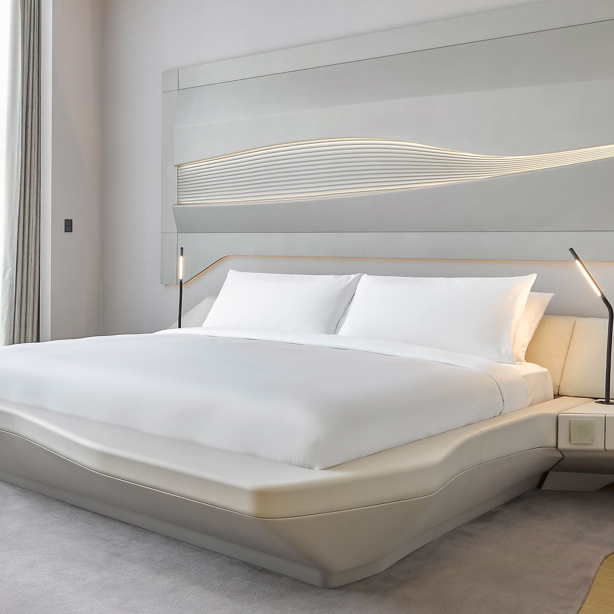 a bed with white sheets and a lamp on the side