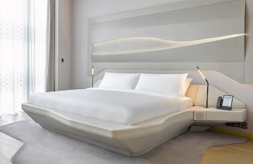 a bed with white sheets and a lamp on the side