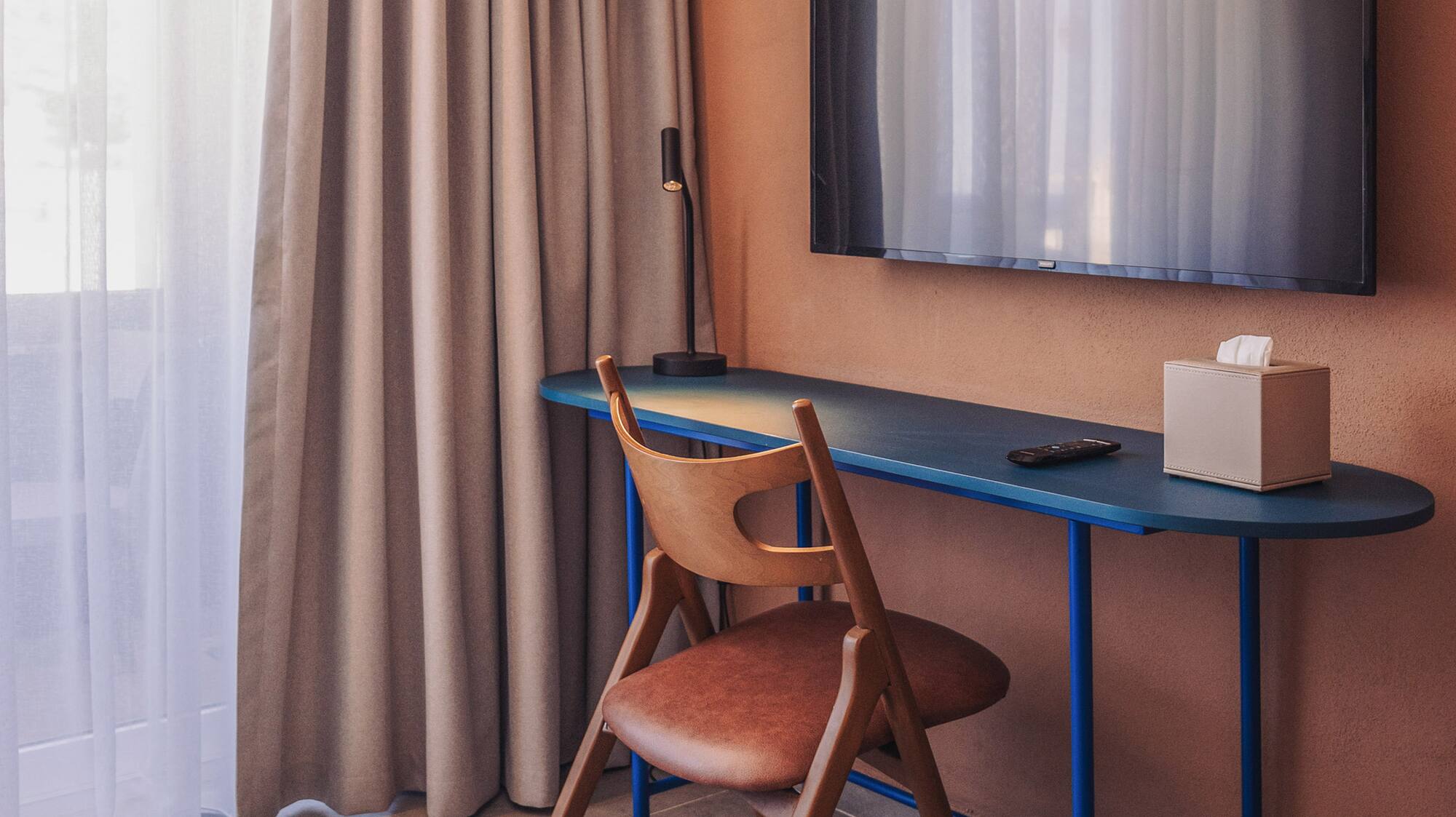 a desk and chair in a room with a tv on the wall
