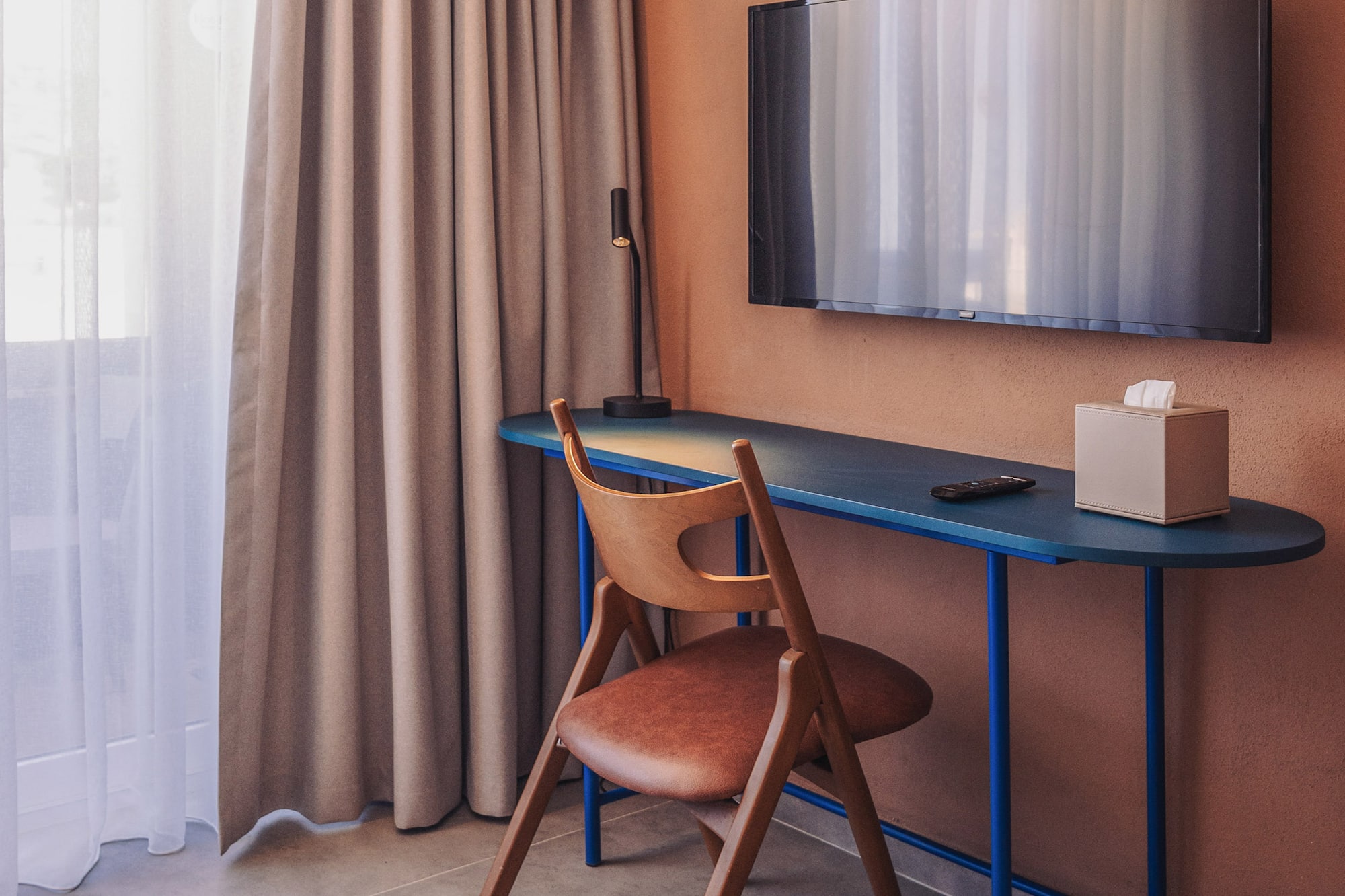 a desk and chair in a room with a tv on the wall