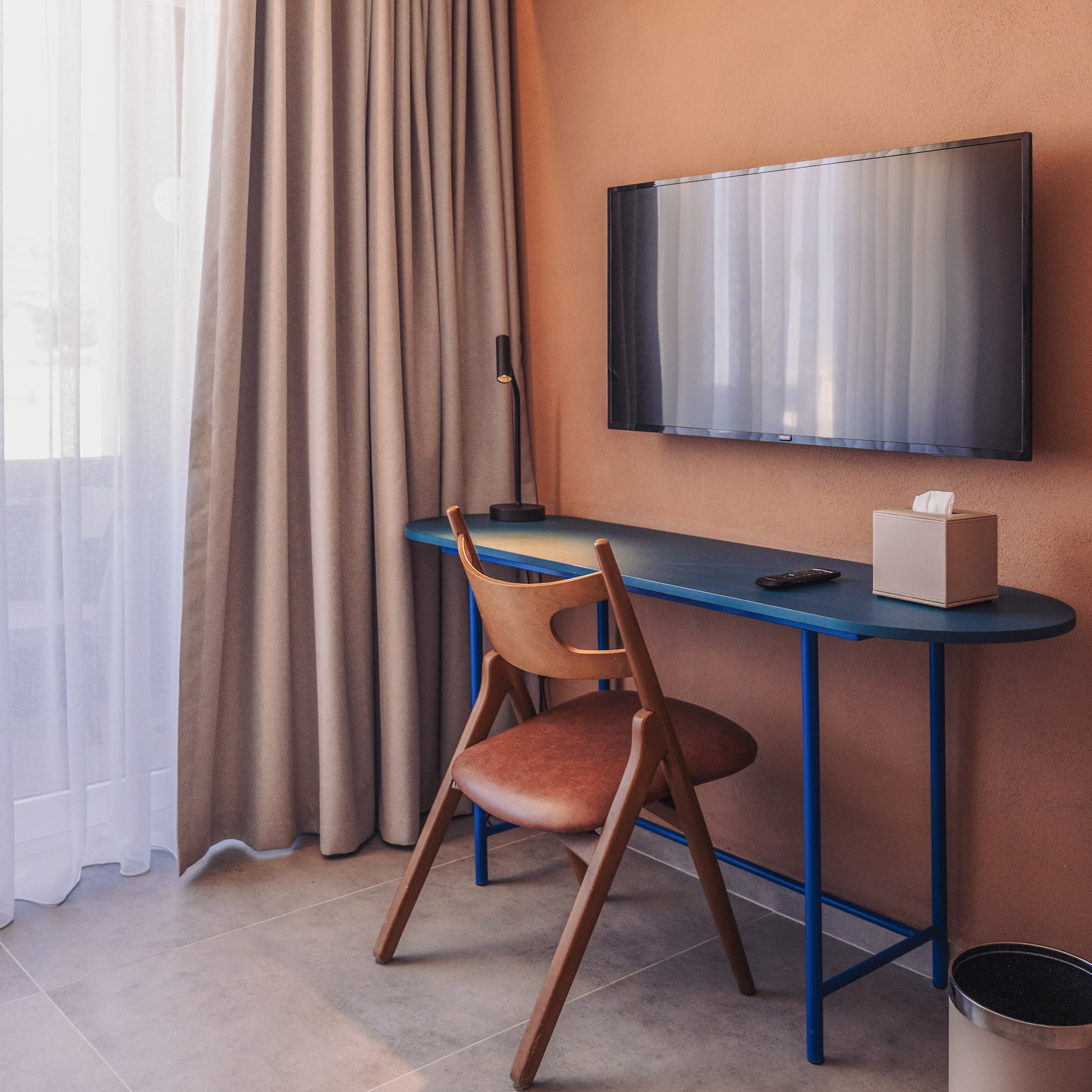 a desk and chair in a room with a tv on the wall