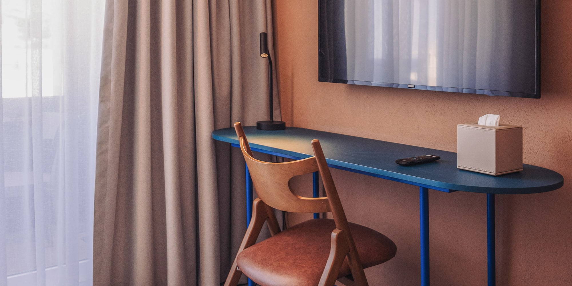 a desk and chair in a room with a tv on the wall