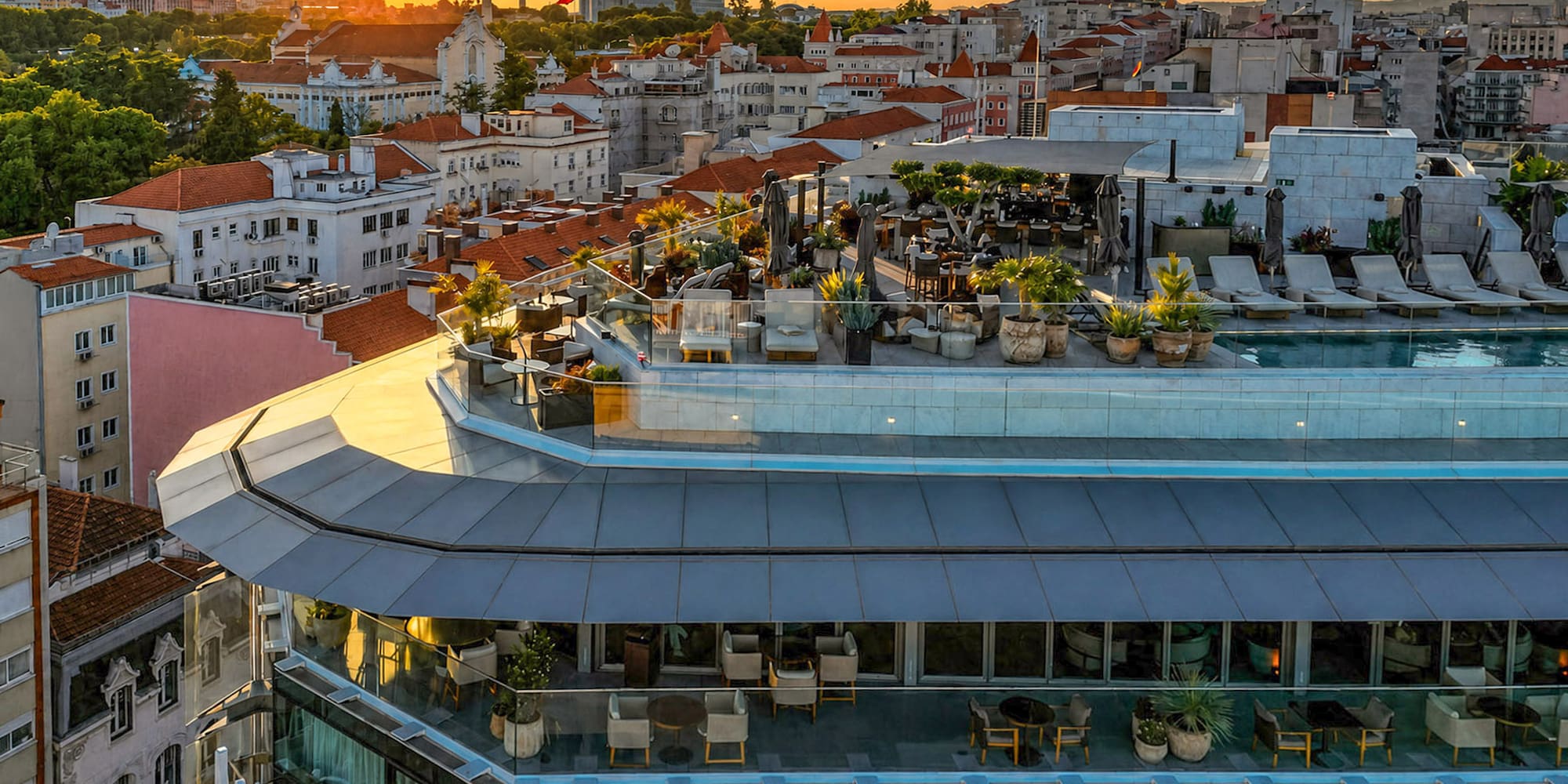 Luxury hotel rooftop pool and bar overlooking Lisbon at sunset.