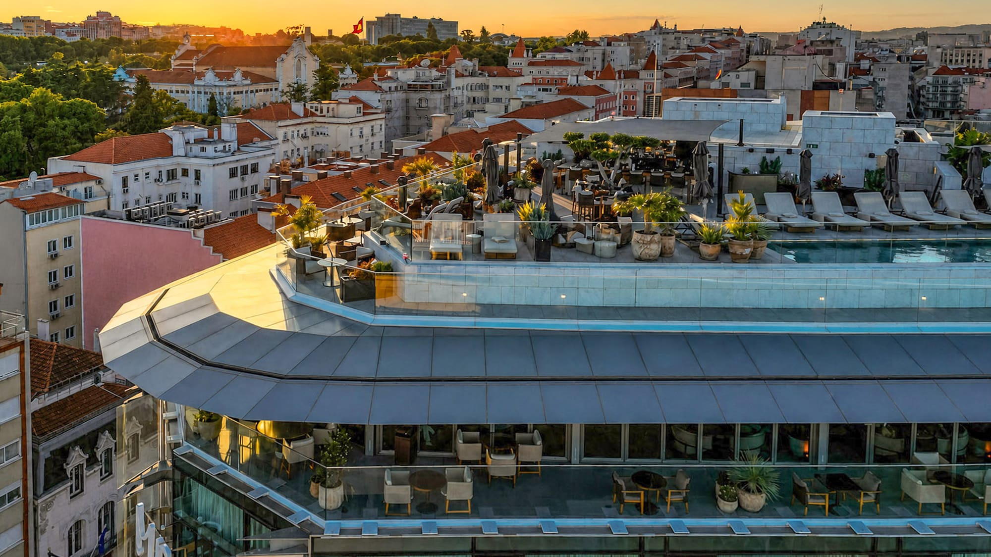 Lisbon rooftop pool and bar with panoramic city views at sunset.