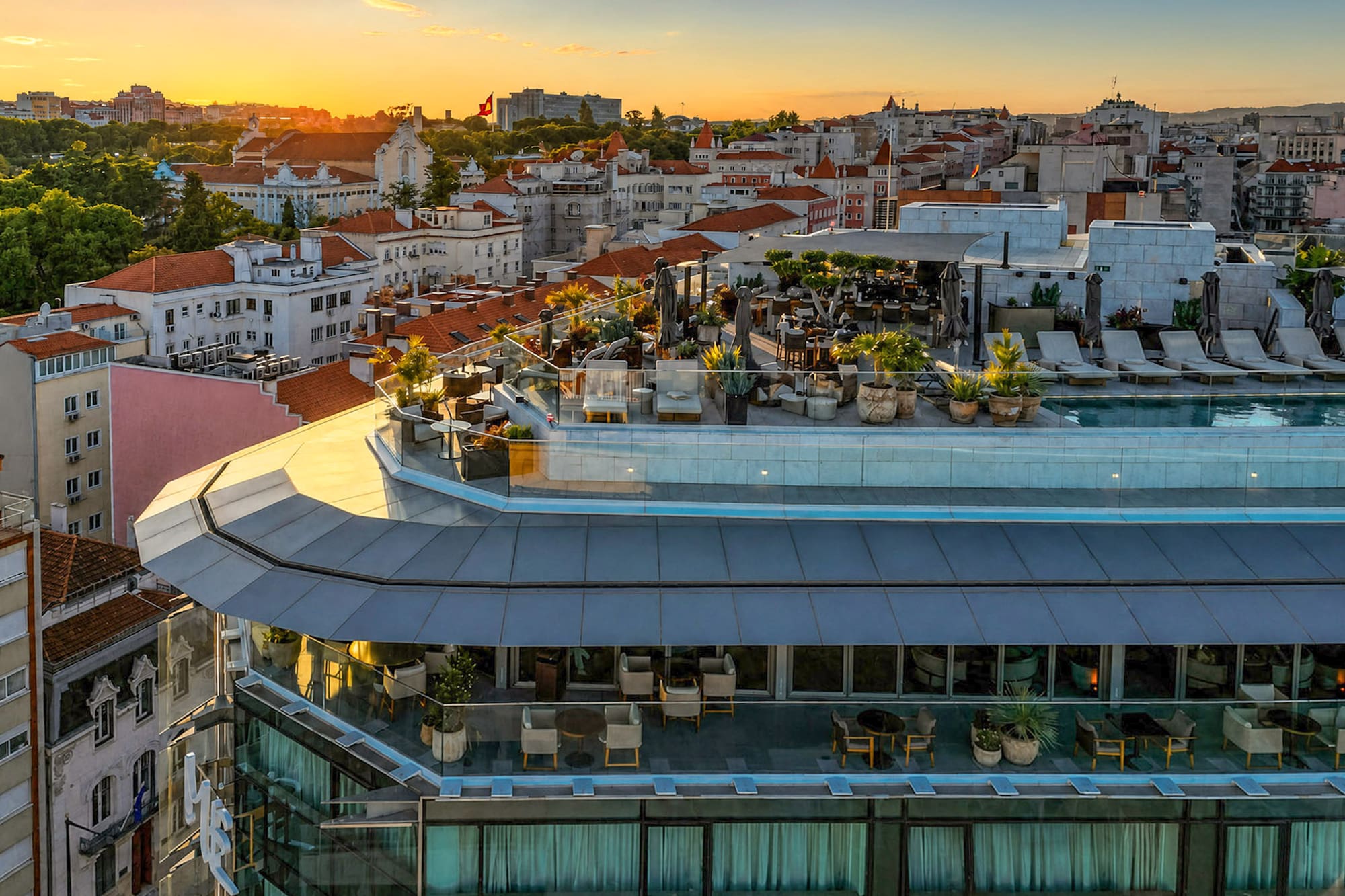 Lisbon rooftop pool and terrace at sunset with city view and lounge area.