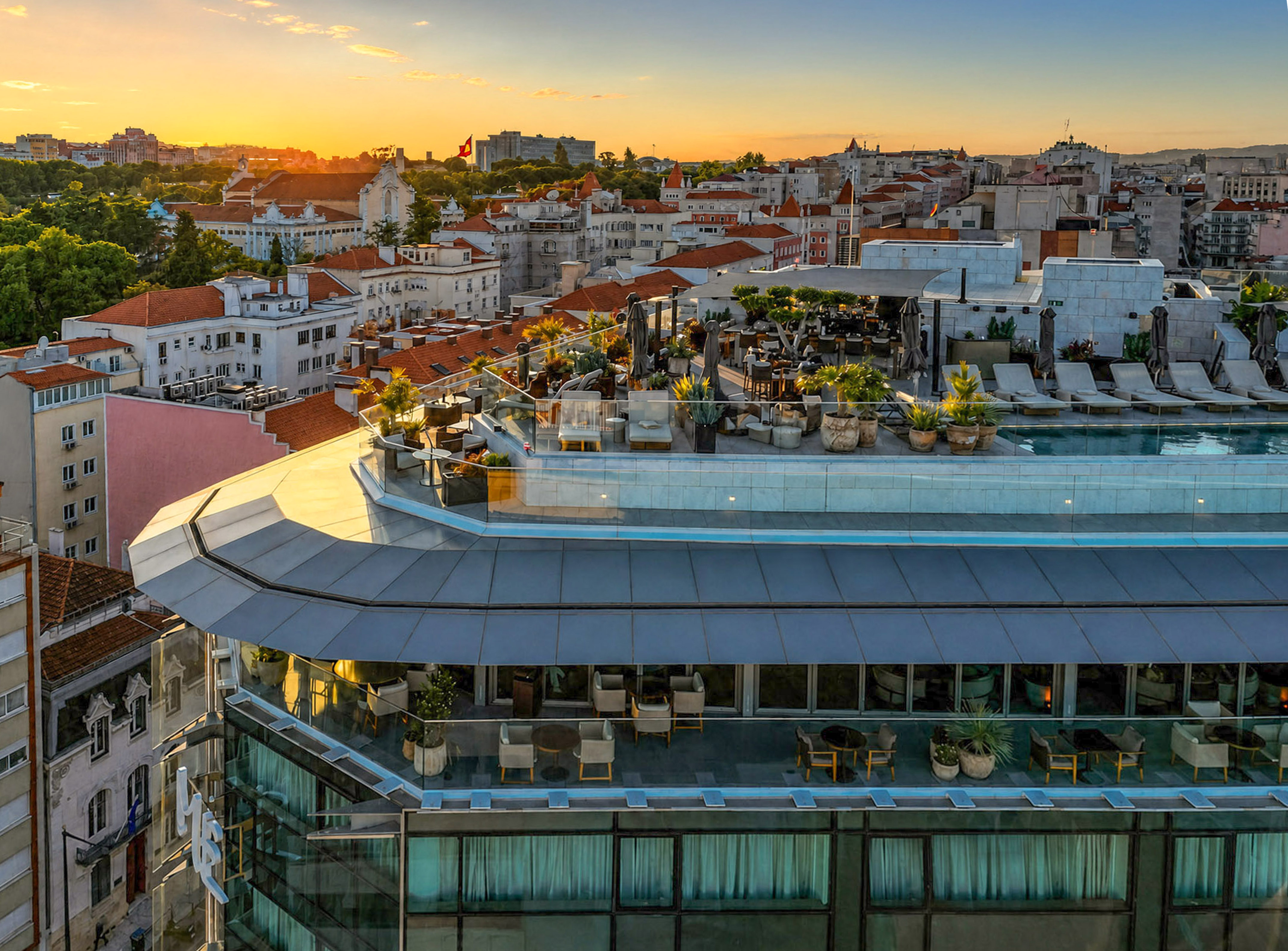 Lisbon rooftop pool and terrace at sunset with city view and lounge area.