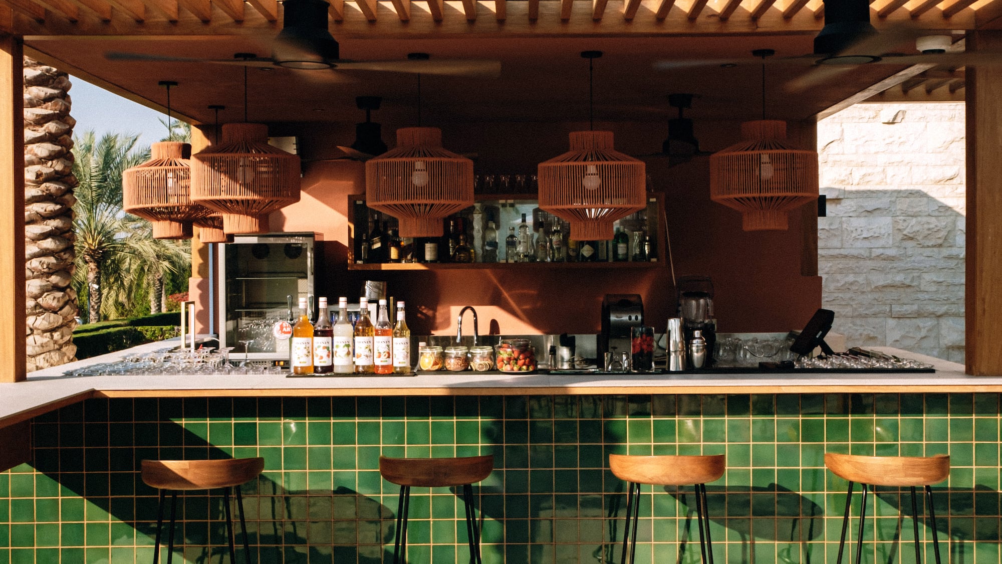 a bar with stools and a green tile wall