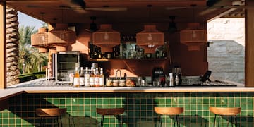 a bar with stools and a green tile wall