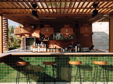 a bar with stools and a green tile wall