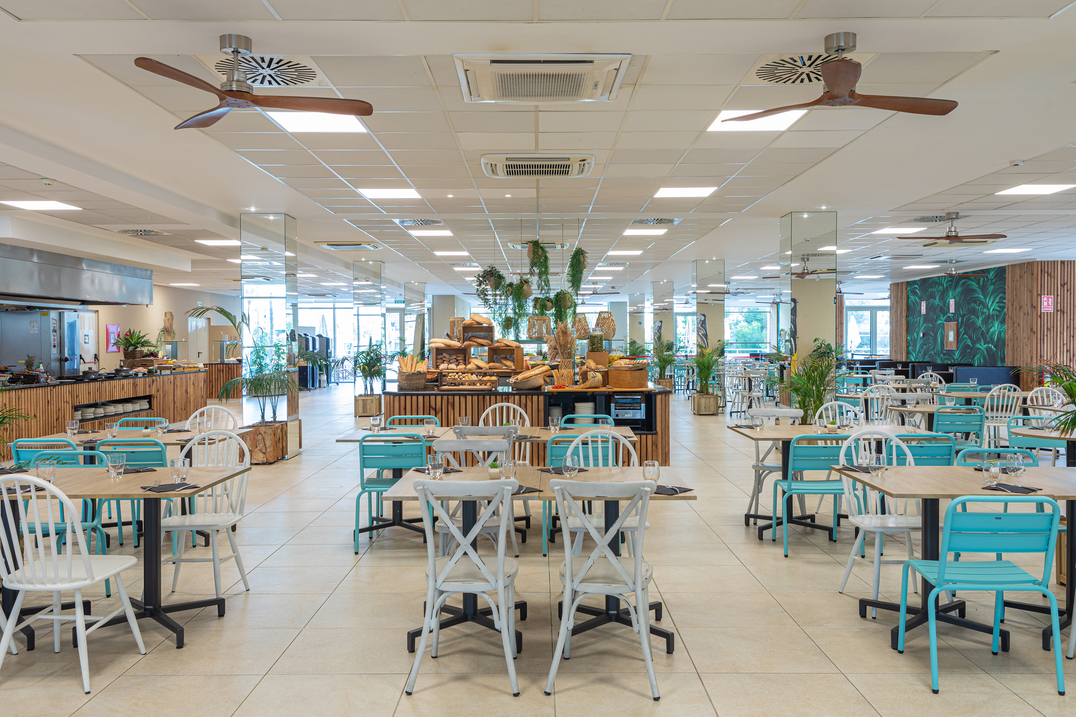 Modern hotel restaurant buffet with diverse seating and tropical decor.