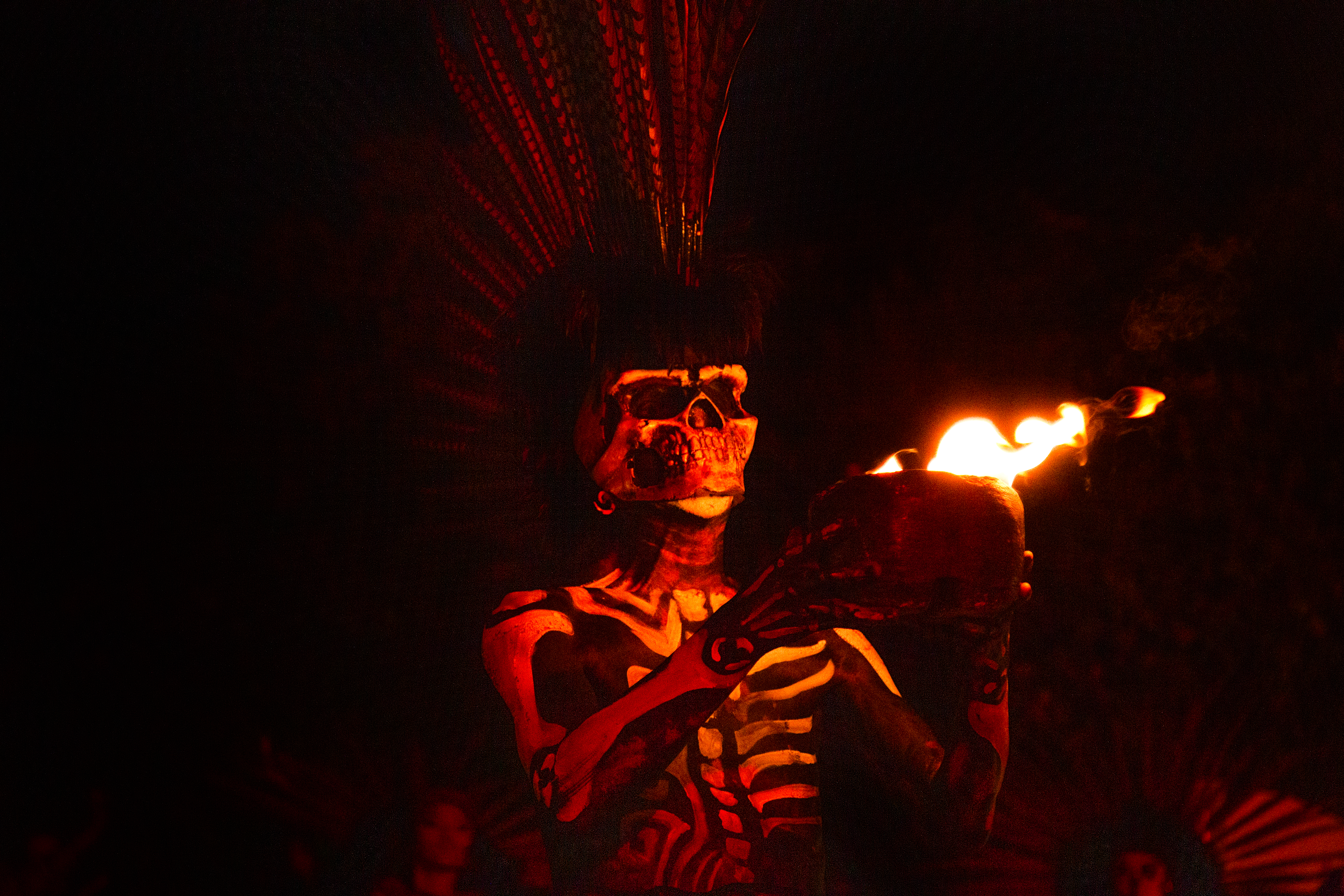 a person in a garment holding a bowl with fire