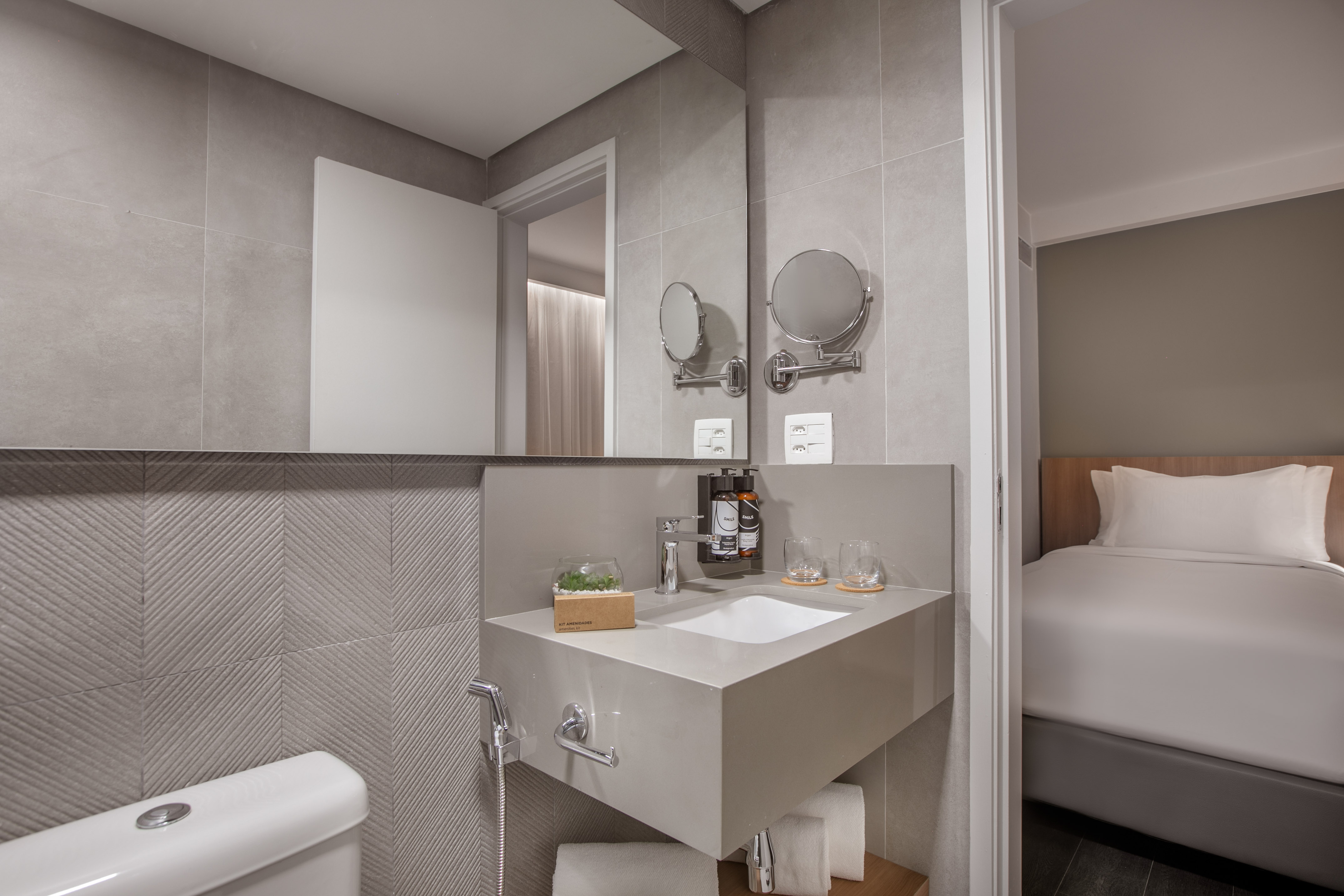 Modern hotel bathroom with grey vanity, sink, toilet, adjacent bedroom. - The Loft for Families - INNSiDE São Paulo Higienópolis, Sao Paulo