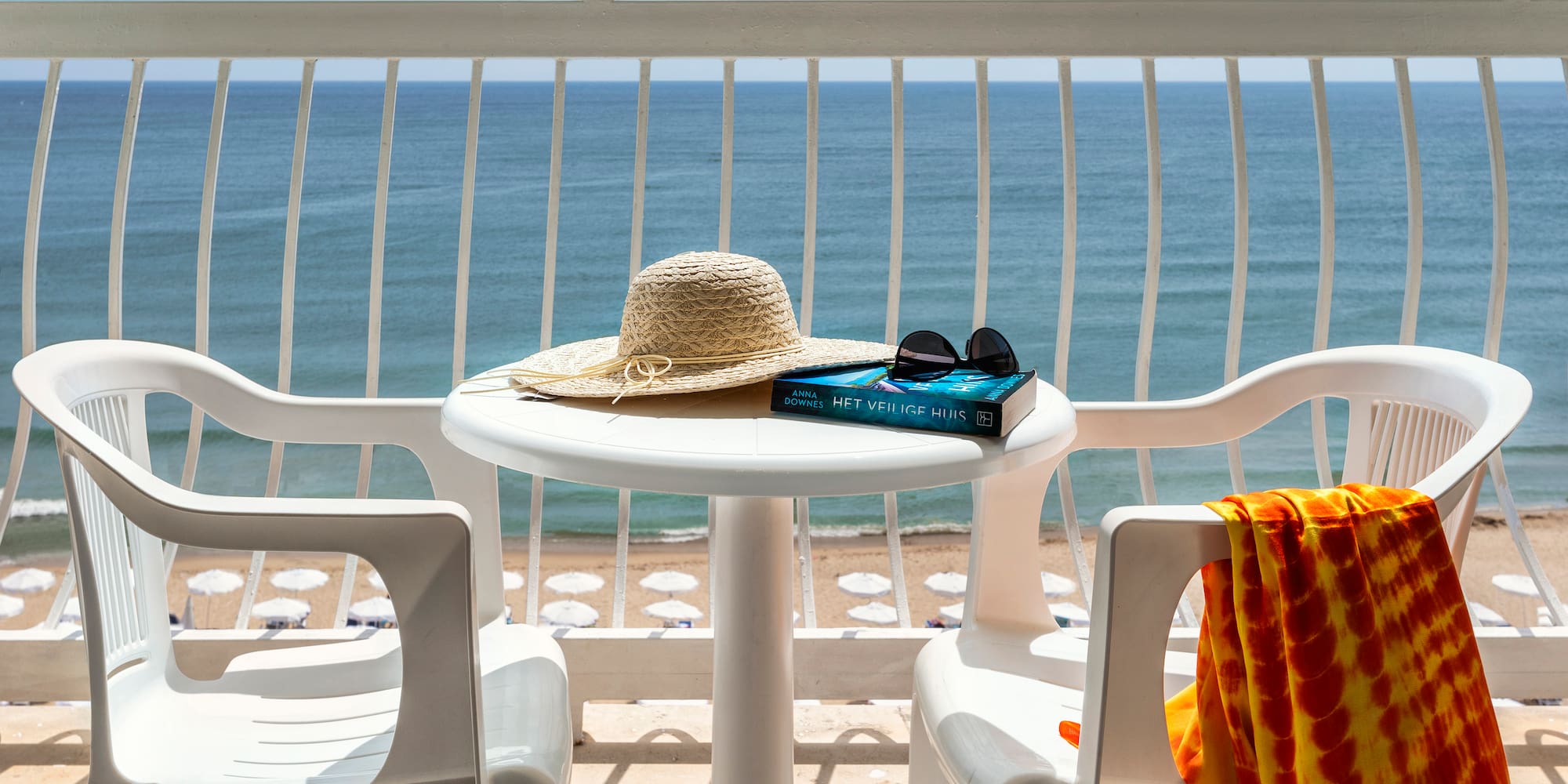 a table with a hat and sunglasses on it and a towel on a beach