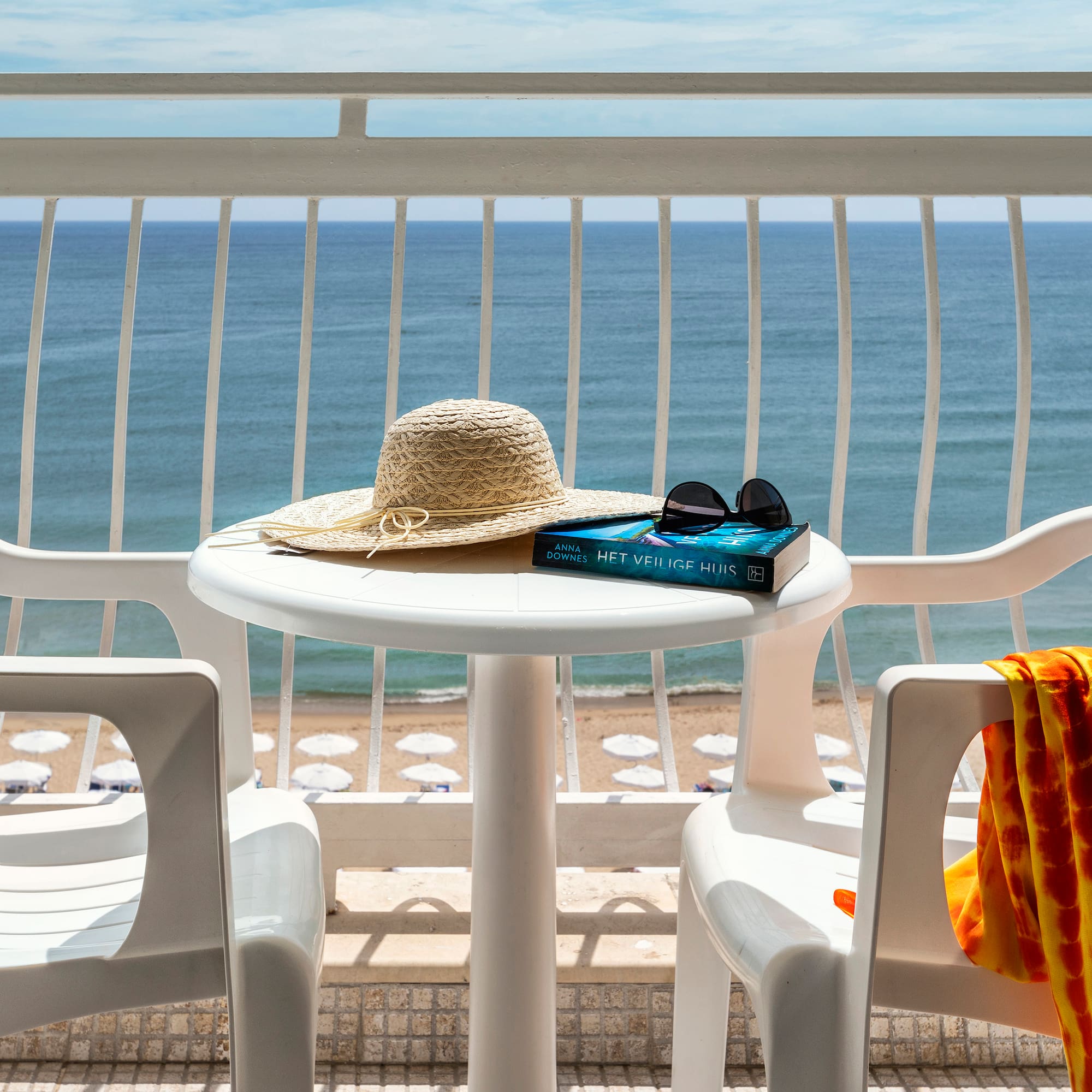 a table with a hat and sunglasses on it and a towel on a beach