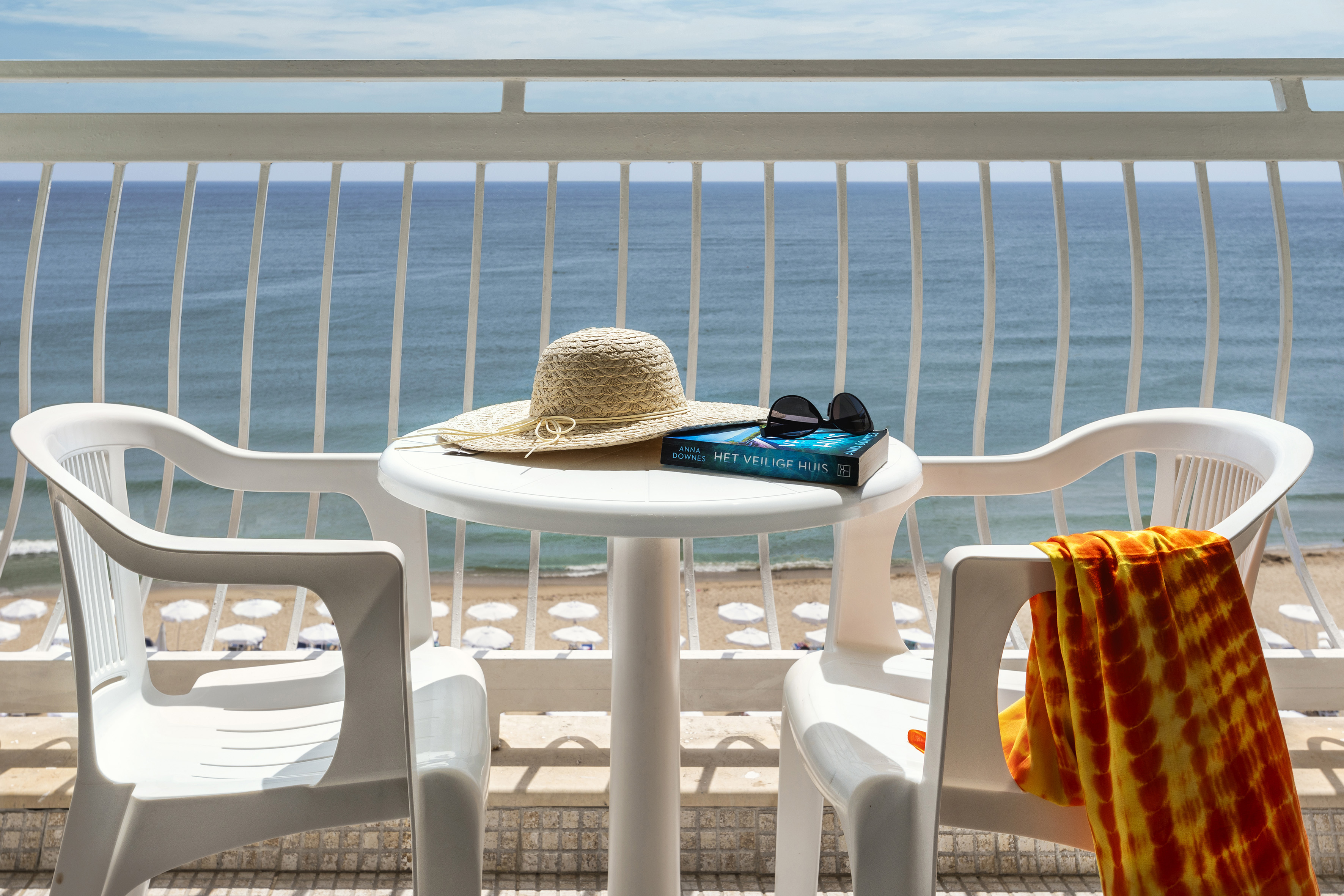 a table with a hat and sunglasses on it and a towel on a beach