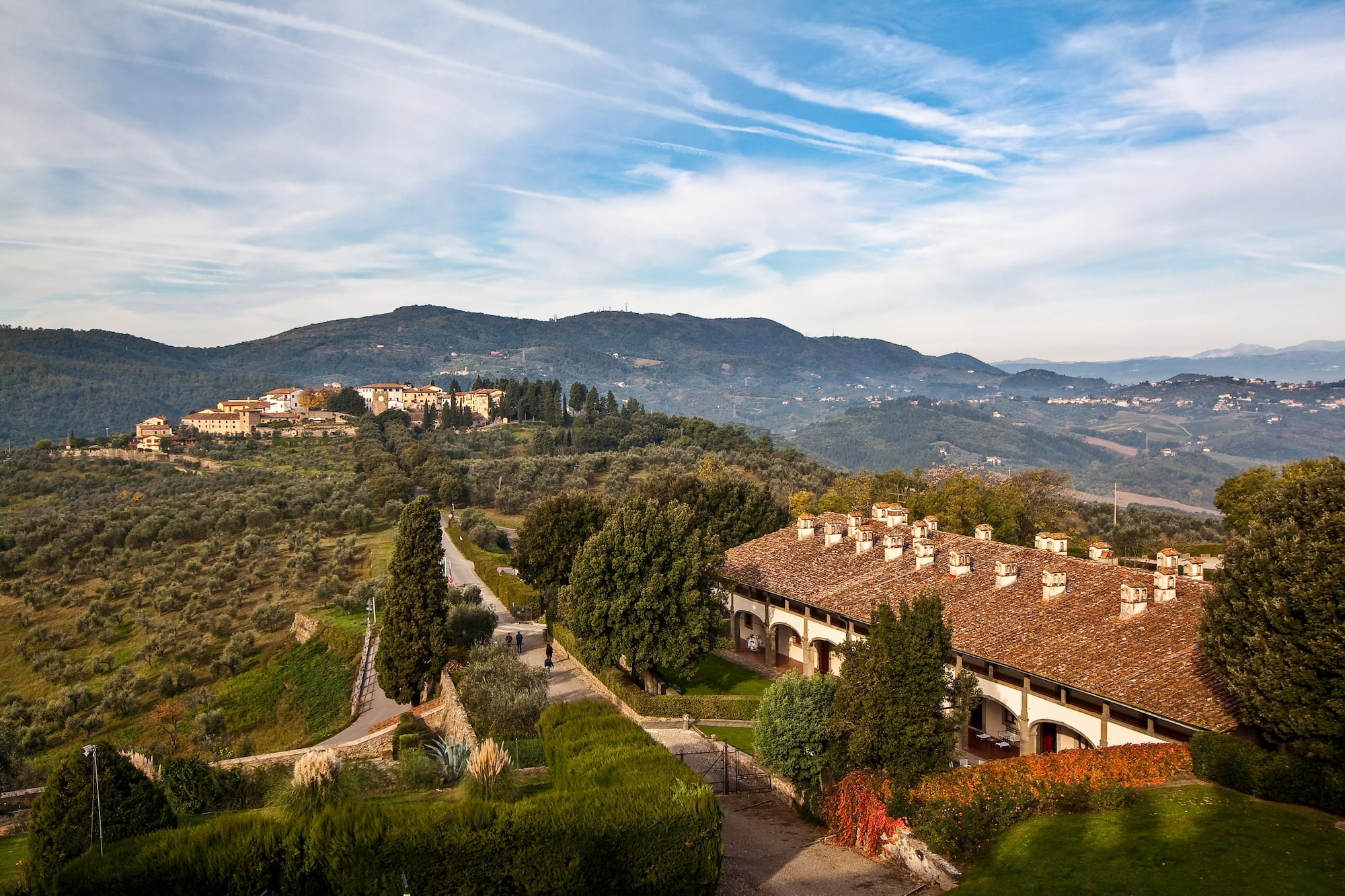 Tuscan hills, olive groves, historic village, and traditional Italian villa.
