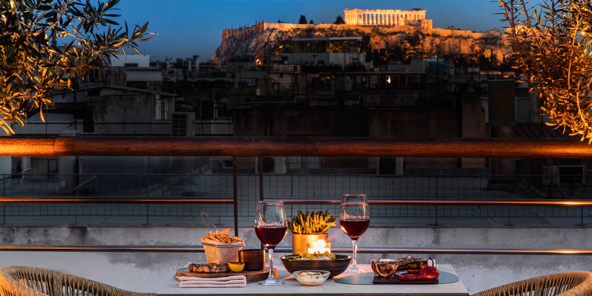 Candlelit rooftop dinner in Athens with Acropolis view at sunset.