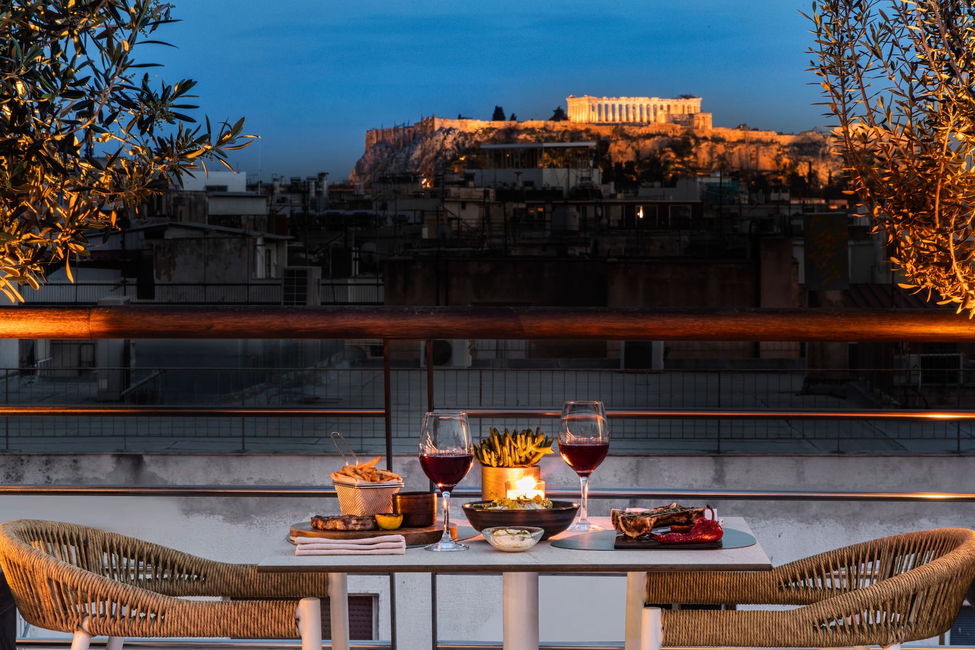 Candlelit rooftop dinner in Athens with Acropolis view at sunset.