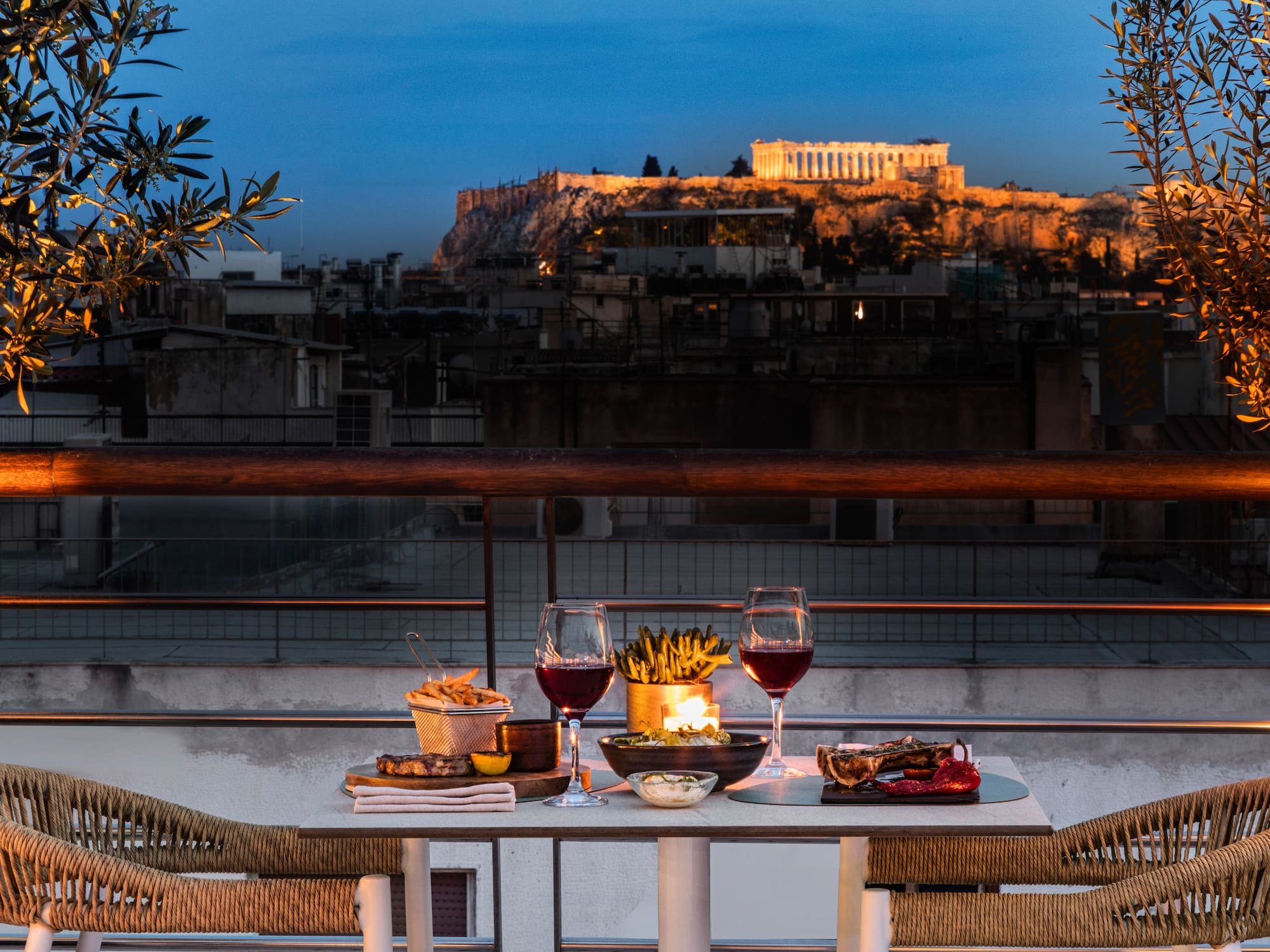 Rooftop dinner overlooking the illuminated Parthenon in Athens at dusk.