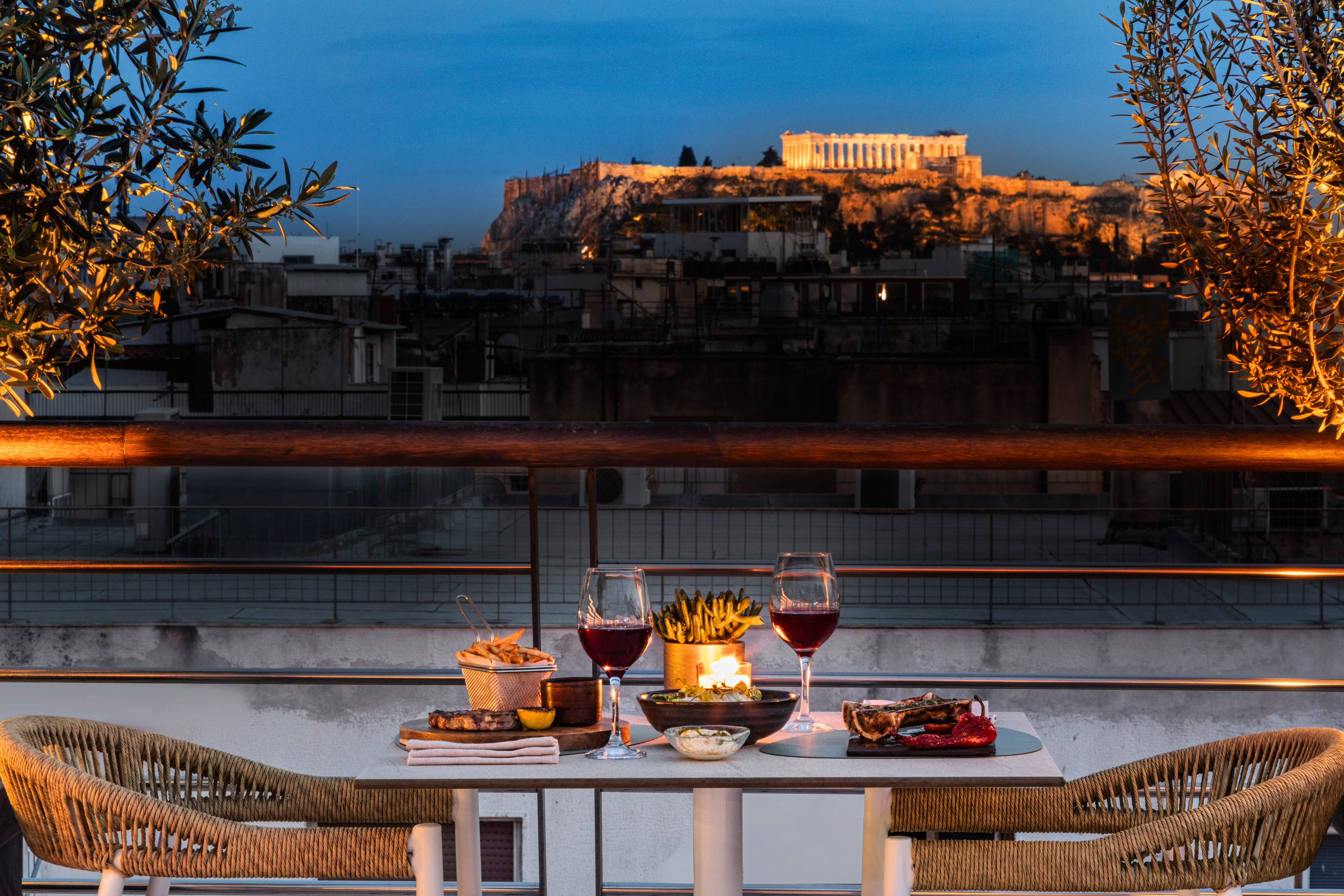 Candlelit rooftop dinner in Athens with Acropolis view at sunset.