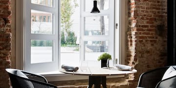 a table and chairs in a room with a brick wall and a window