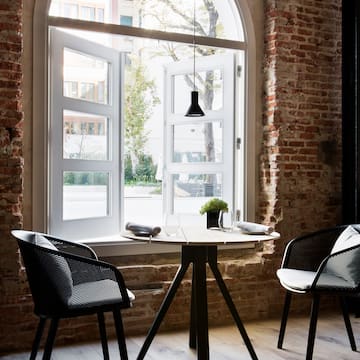 a table and chairs in a room with a brick wall and a window