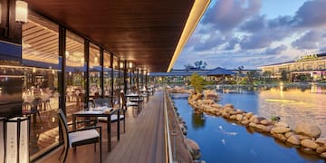 a restaurant with tables and chairs on a deck overlooking a body of water