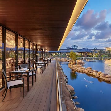 a restaurant with tables and chairs on a deck overlooking a body of water