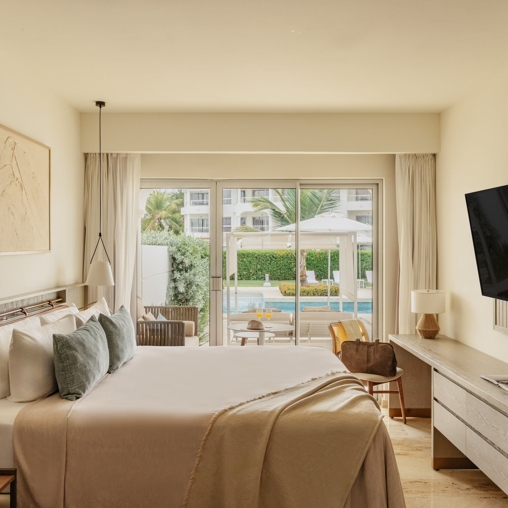 Modern hotel bedroom with king bed, pool view, and outdoor patio.