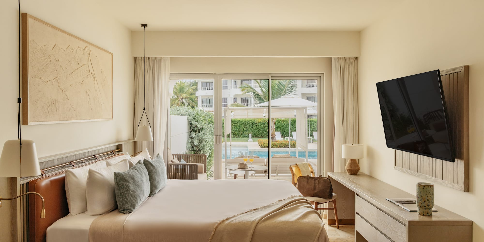 Modern hotel bedroom with king bed, pool view, and outdoor patio.
