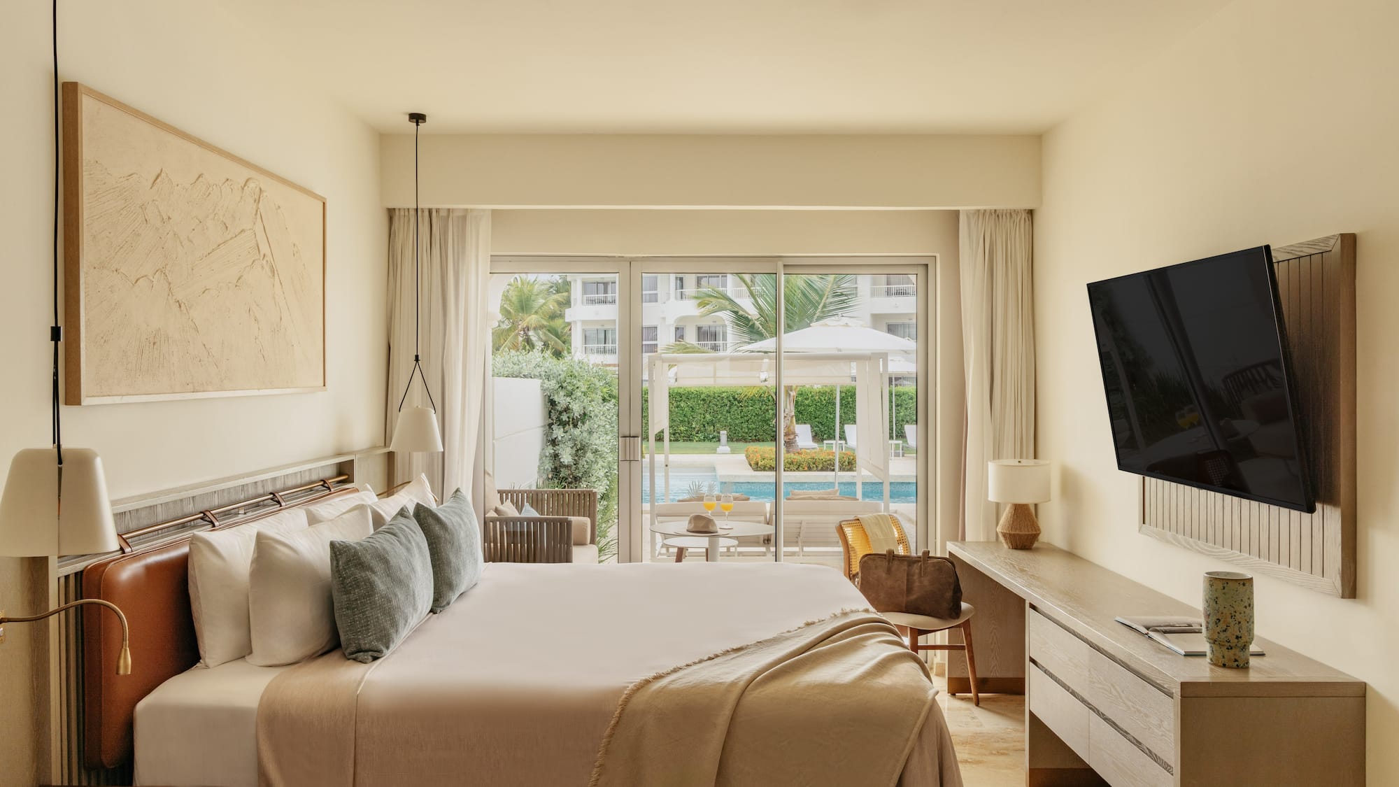 Modern hotel bedroom with king bed, pool view, and outdoor patio.