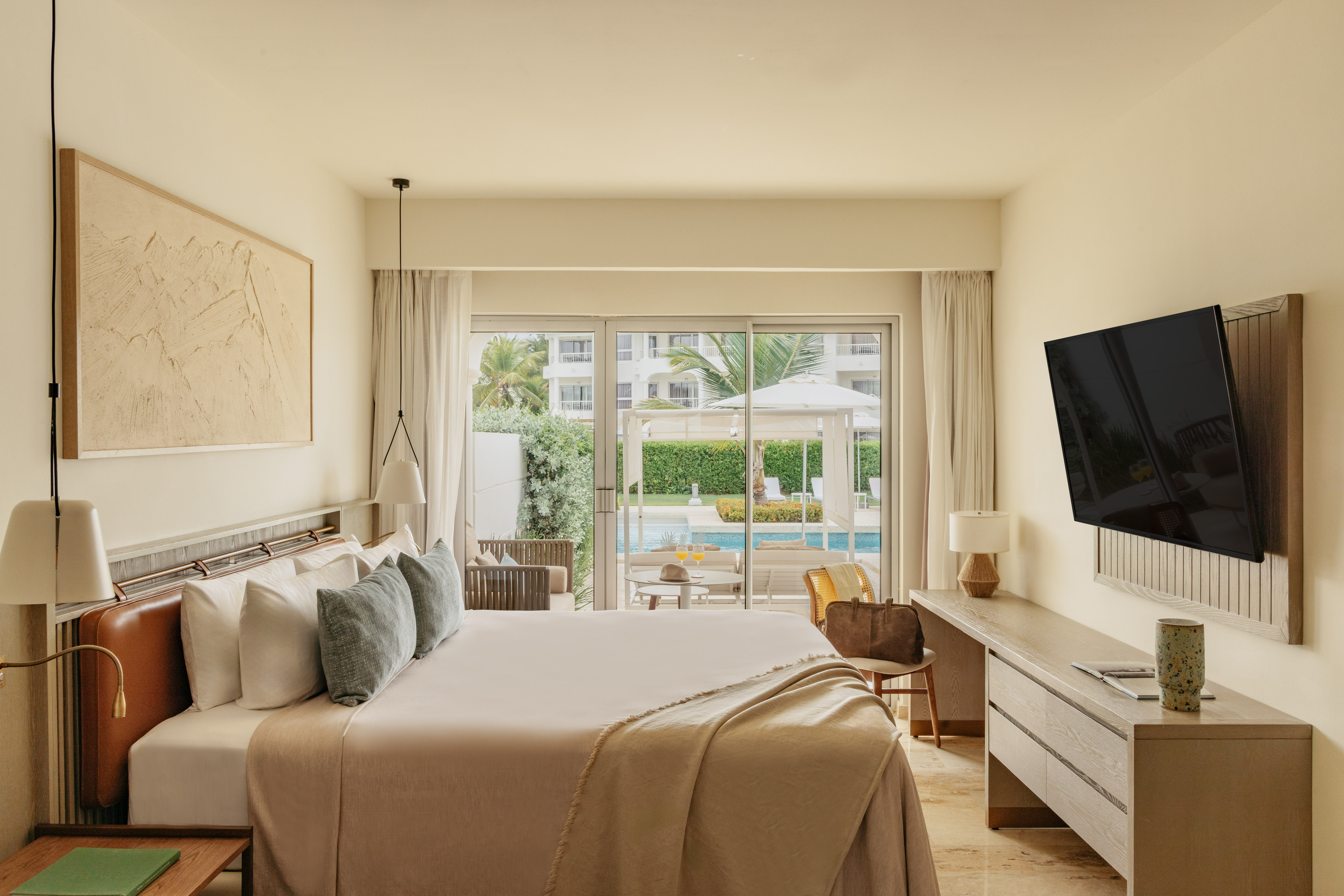 Modern hotel bedroom with king bed, pool view, and outdoor patio.