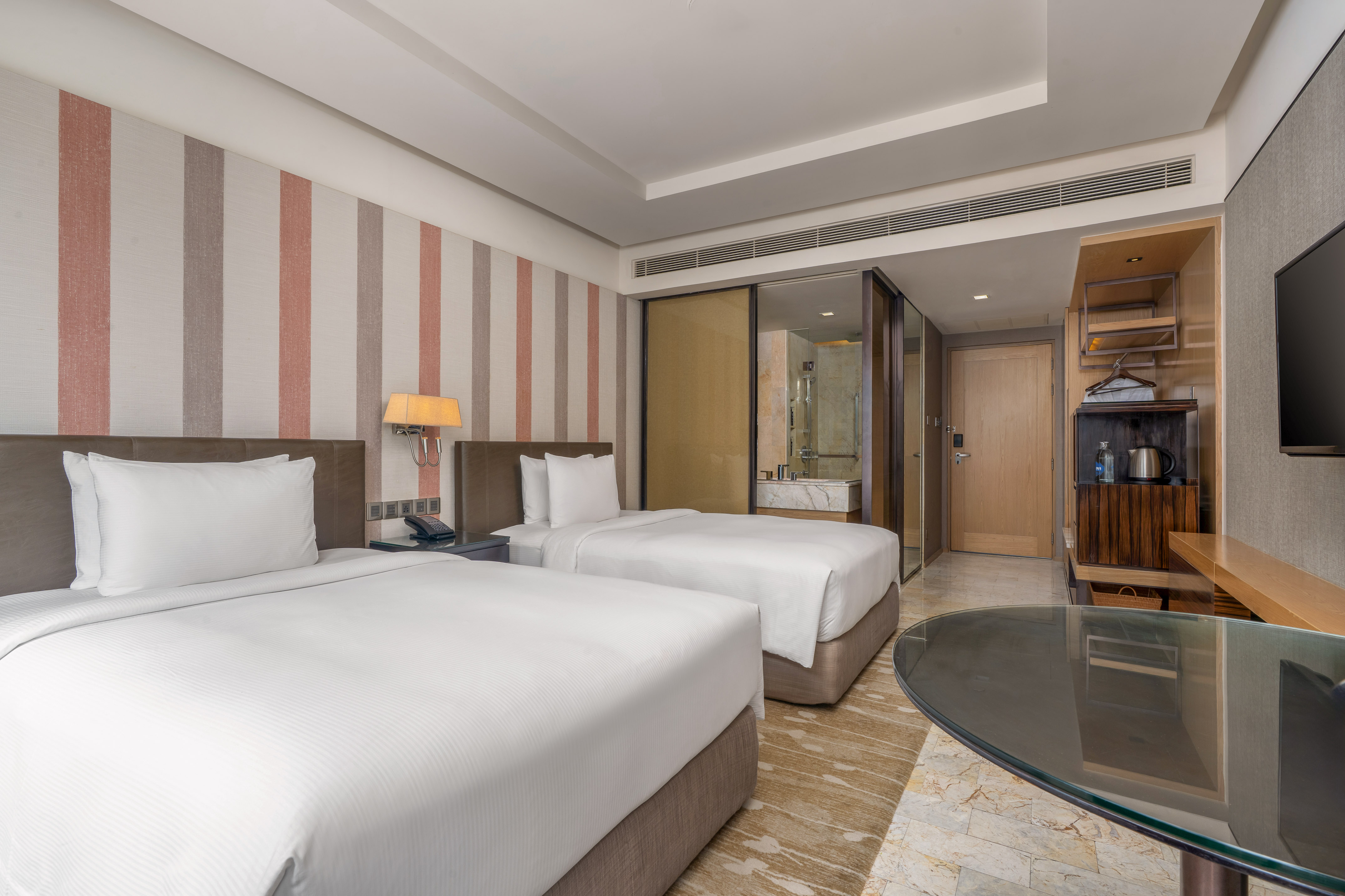 Modern hotel twin bedroom with white linens, striped accent wall, and glass desk. - Guest Room - The Hotel Bangkok Sukhumvit 26 Affiliated by Meliá, بانكوك