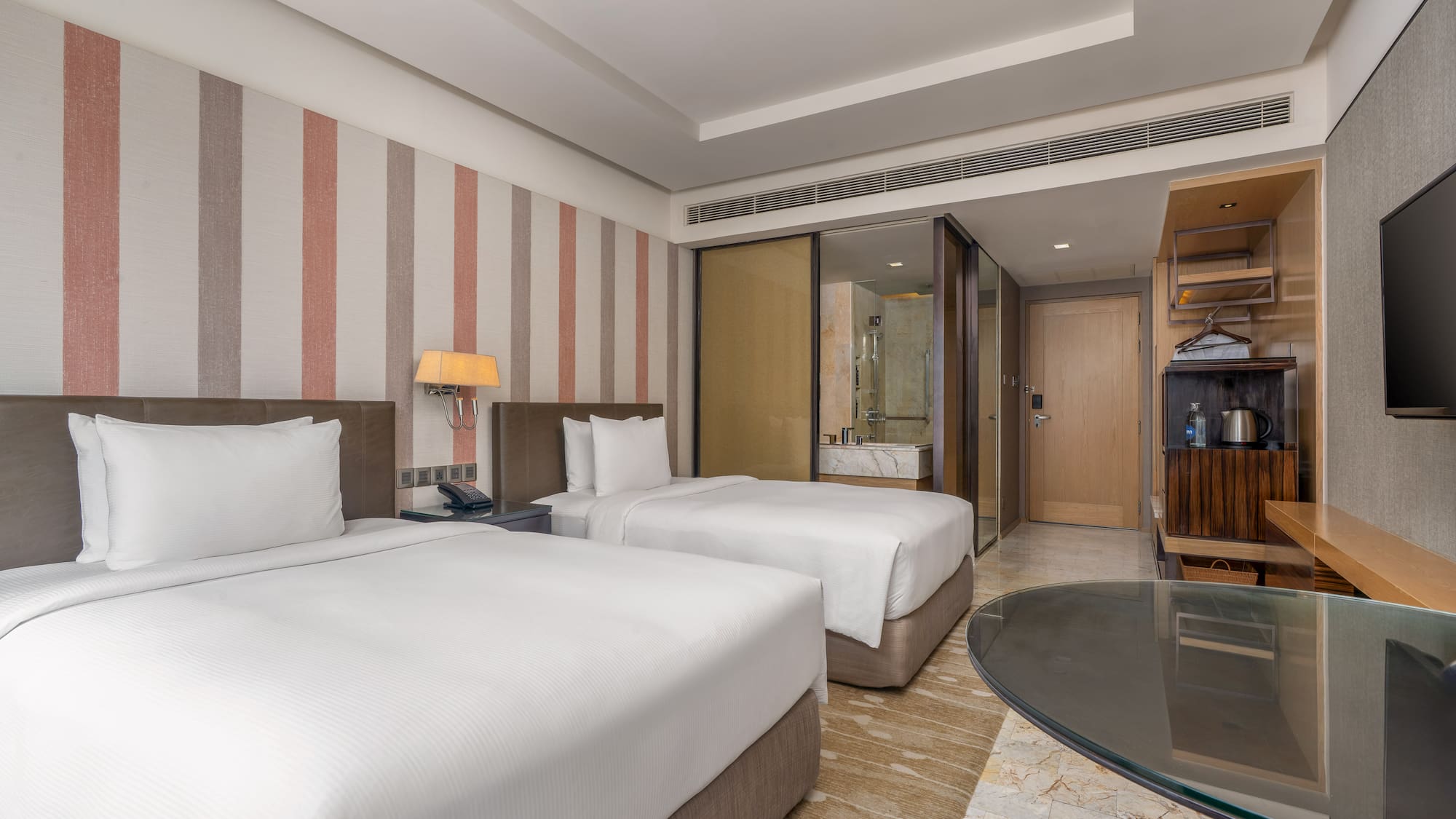 Modern hotel twin bedroom with white linens, striped accent wall, and glass desk. - Guest Room - The Hotel Bangkok Sukhumvit 26 Affiliated by Meliá, بانكوك