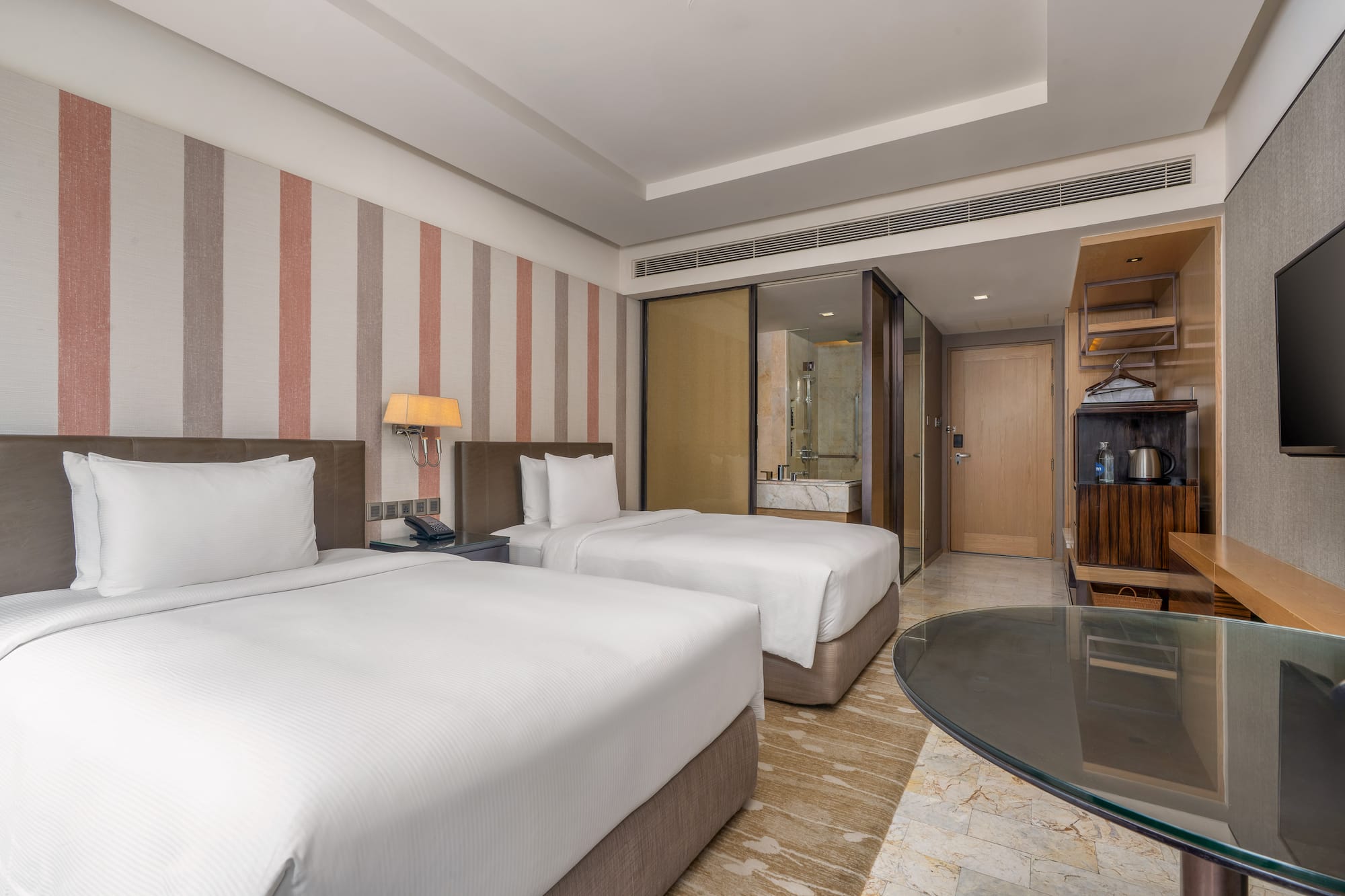 Modern hotel twin bedroom with white linens, striped accent wall, and glass desk. - Guest Room - The Hotel Bangkok Sukhumvit 26 Affiliated by Meliá, Bangkok