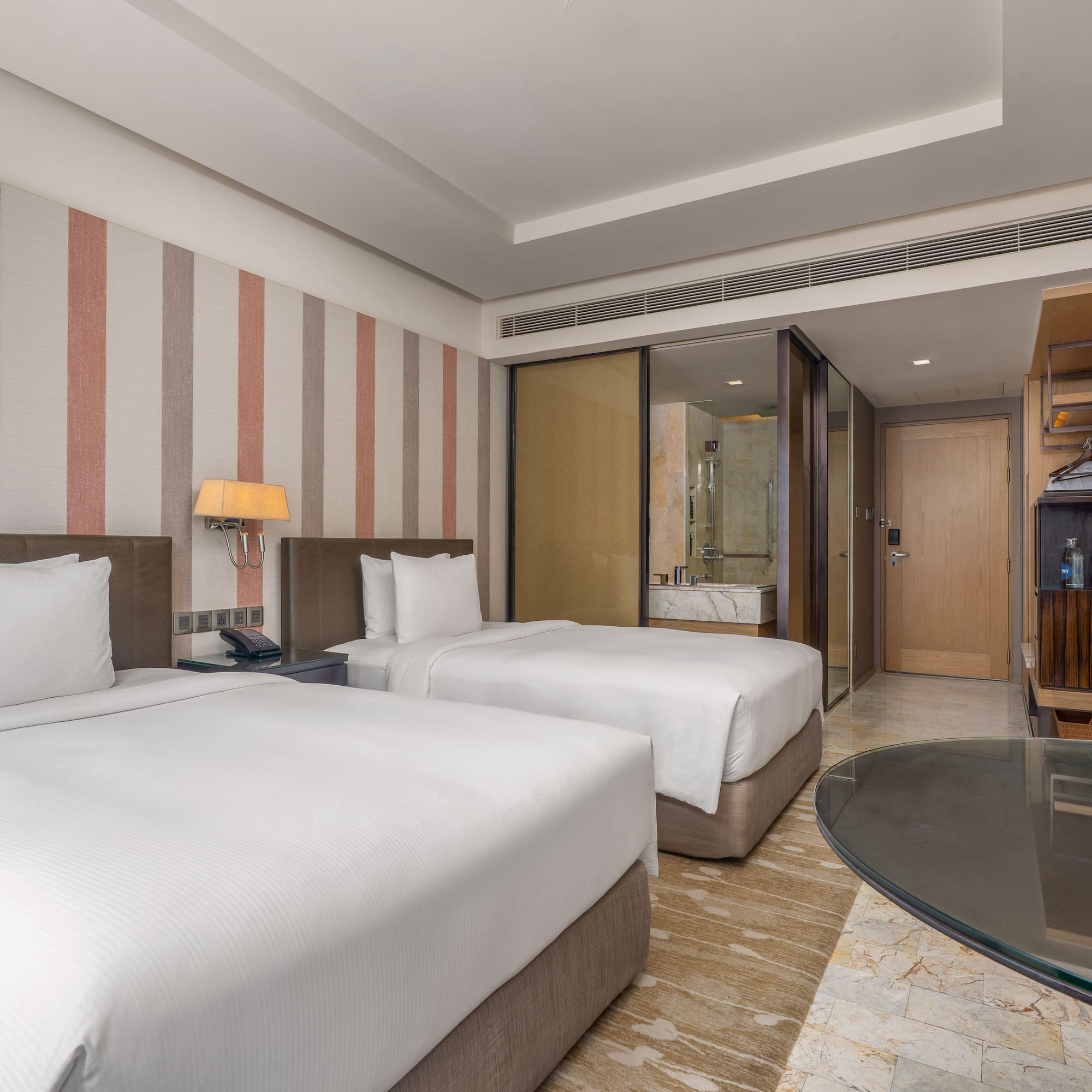 Modern hotel twin bedroom with white linens, striped accent wall, and glass desk. - Guest Room - The Hotel Bangkok Sukhumvit 26 Affiliated by Meliá, Bangkok