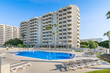 a pool with lounge chairs and a building