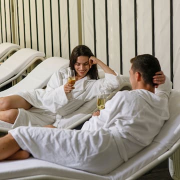 a man and woman in bathrobes sitting on lounge chairs