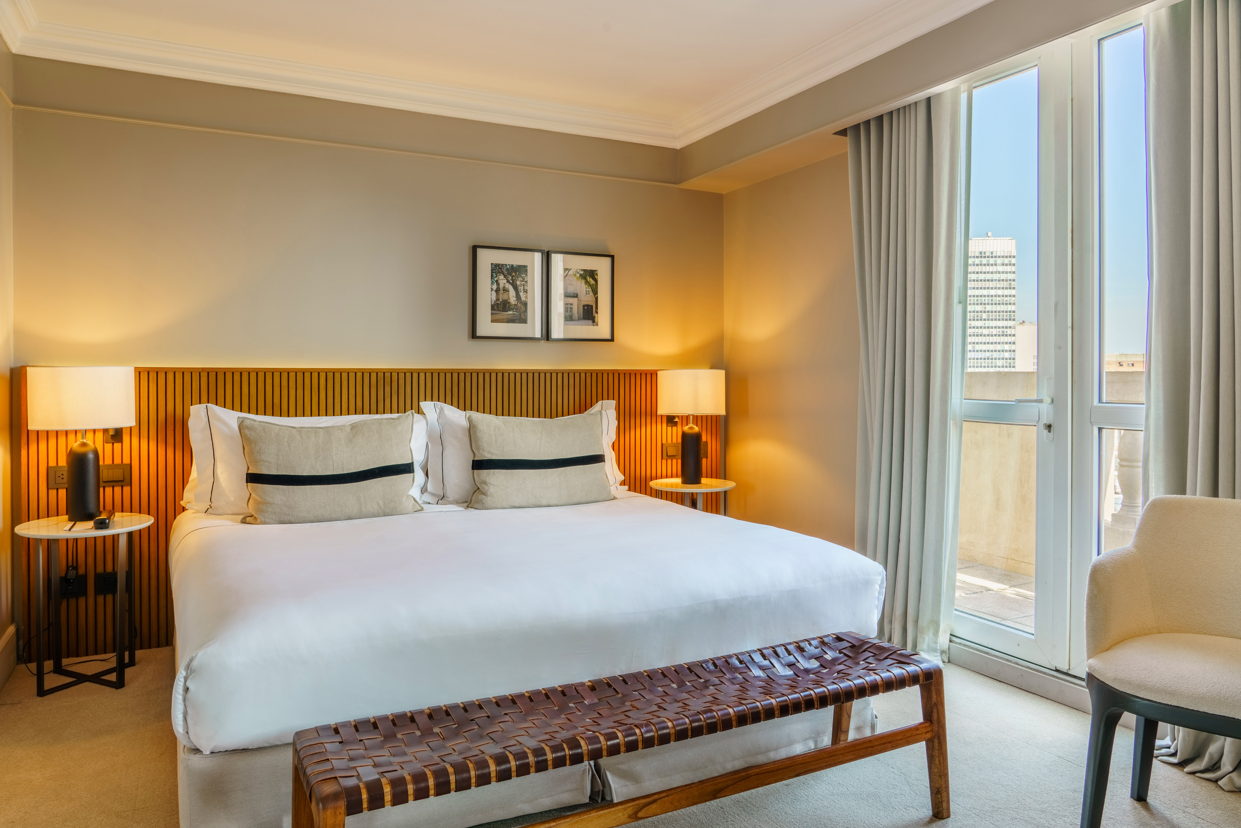 Luxury hotel bedroom with modern king bed, wooden headboard, and city view.