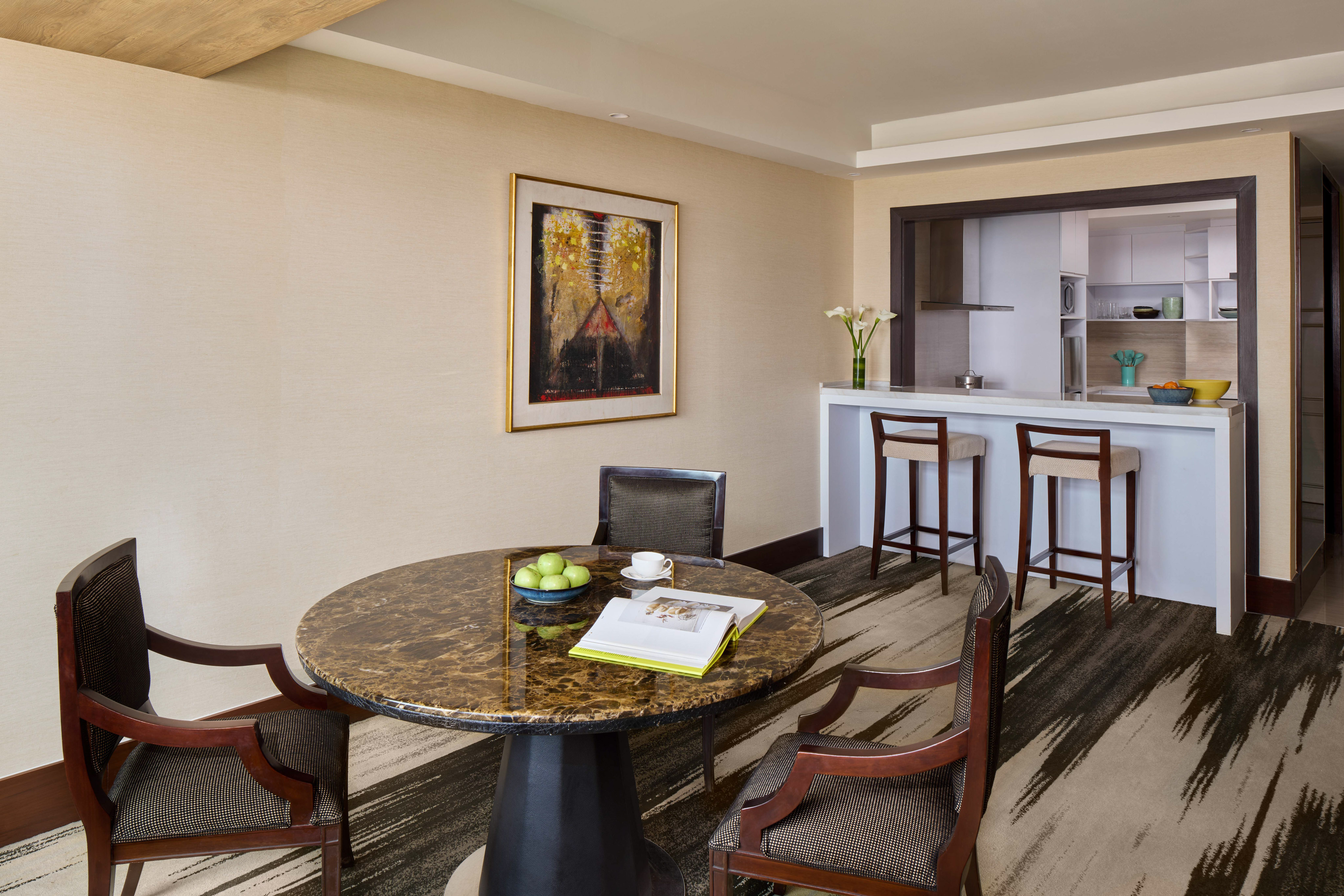 Modern suite dining area with marble table, chairs, and breakfast bar.